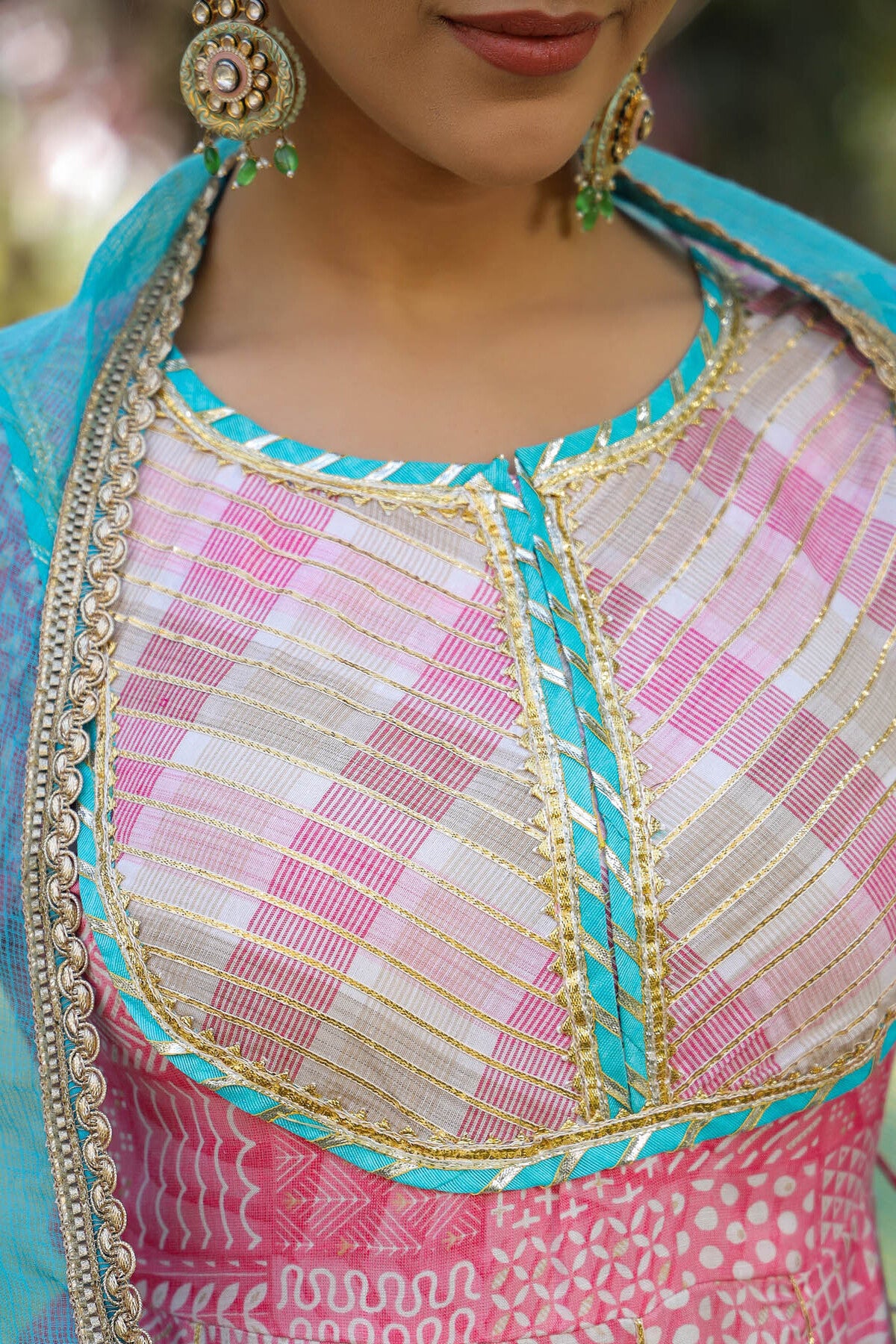 Close-up of a traditional outfit with pink and blue patterns and gold accents.