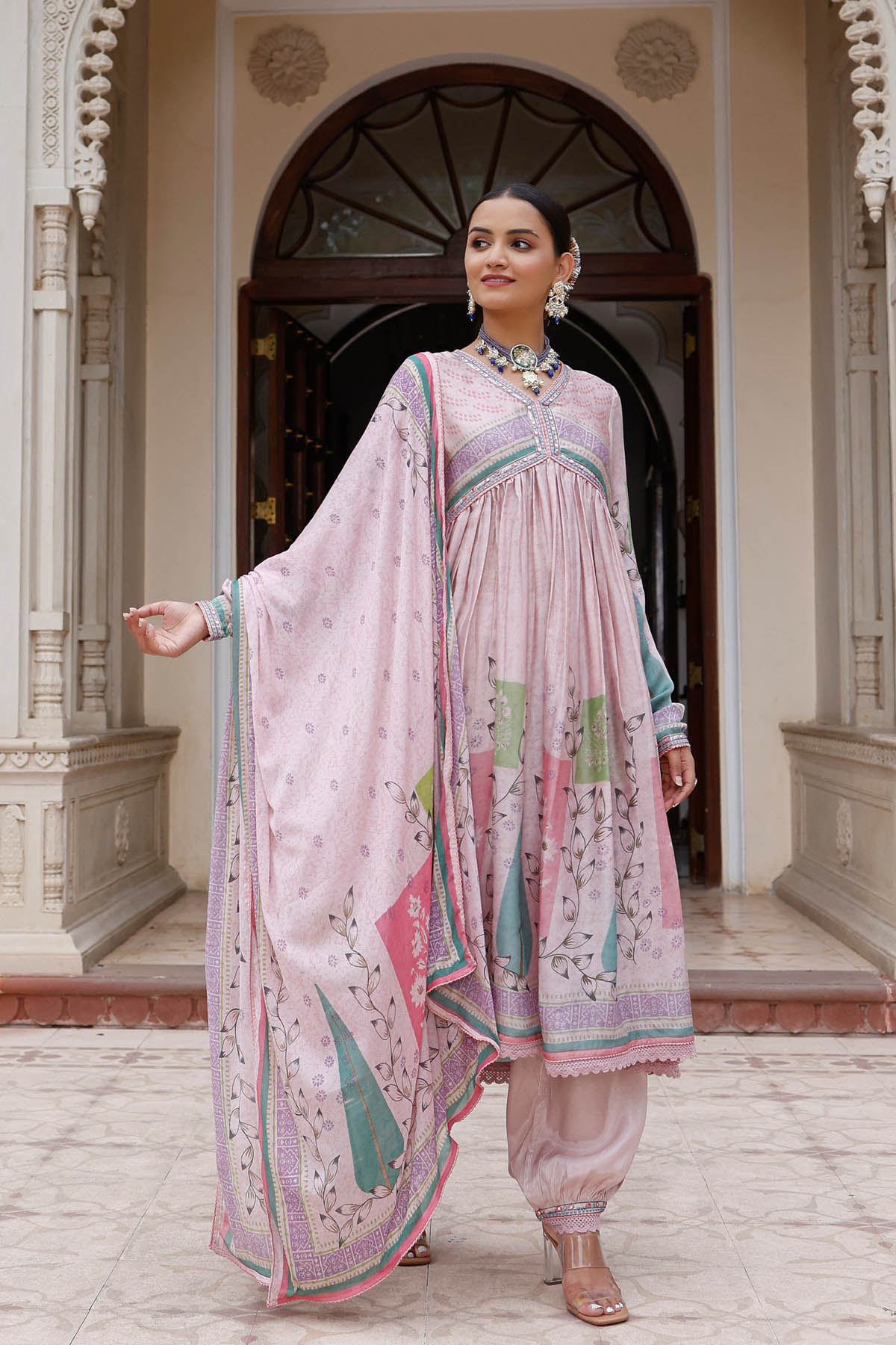 Woman in a traditional outfit standing in front of an archway.