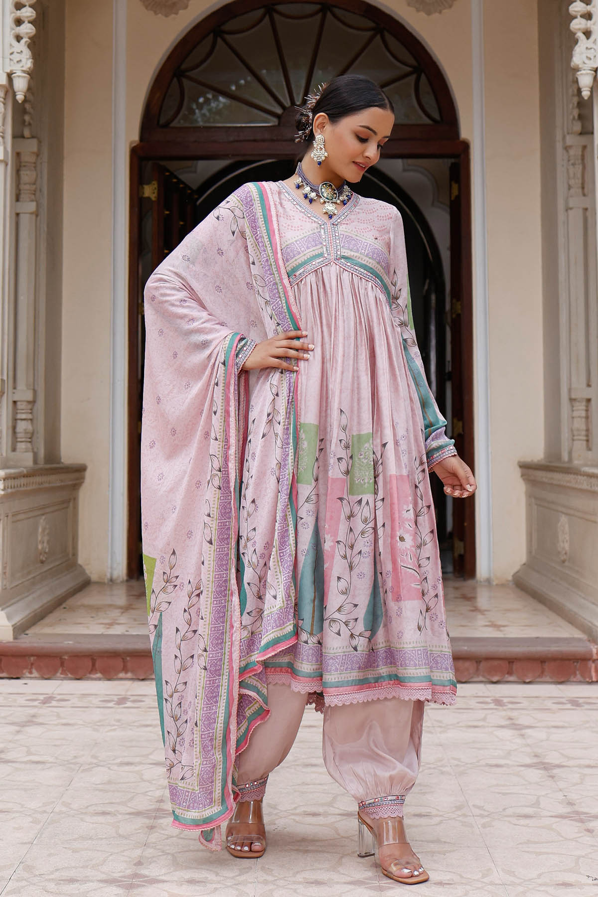 Woman in a traditional outfit standing in front of an archway.