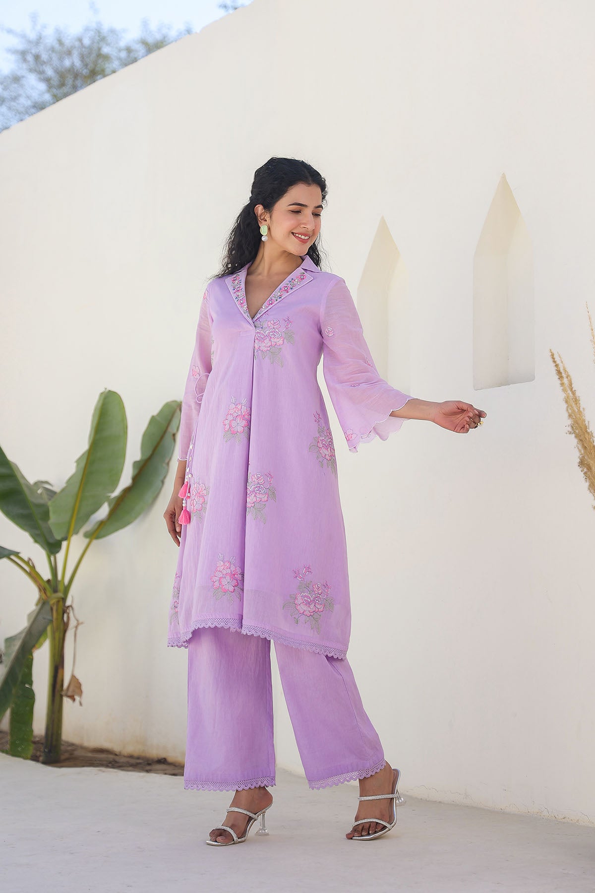 Woman wearing a light purple traditional outfit with floral patterns outdoors.