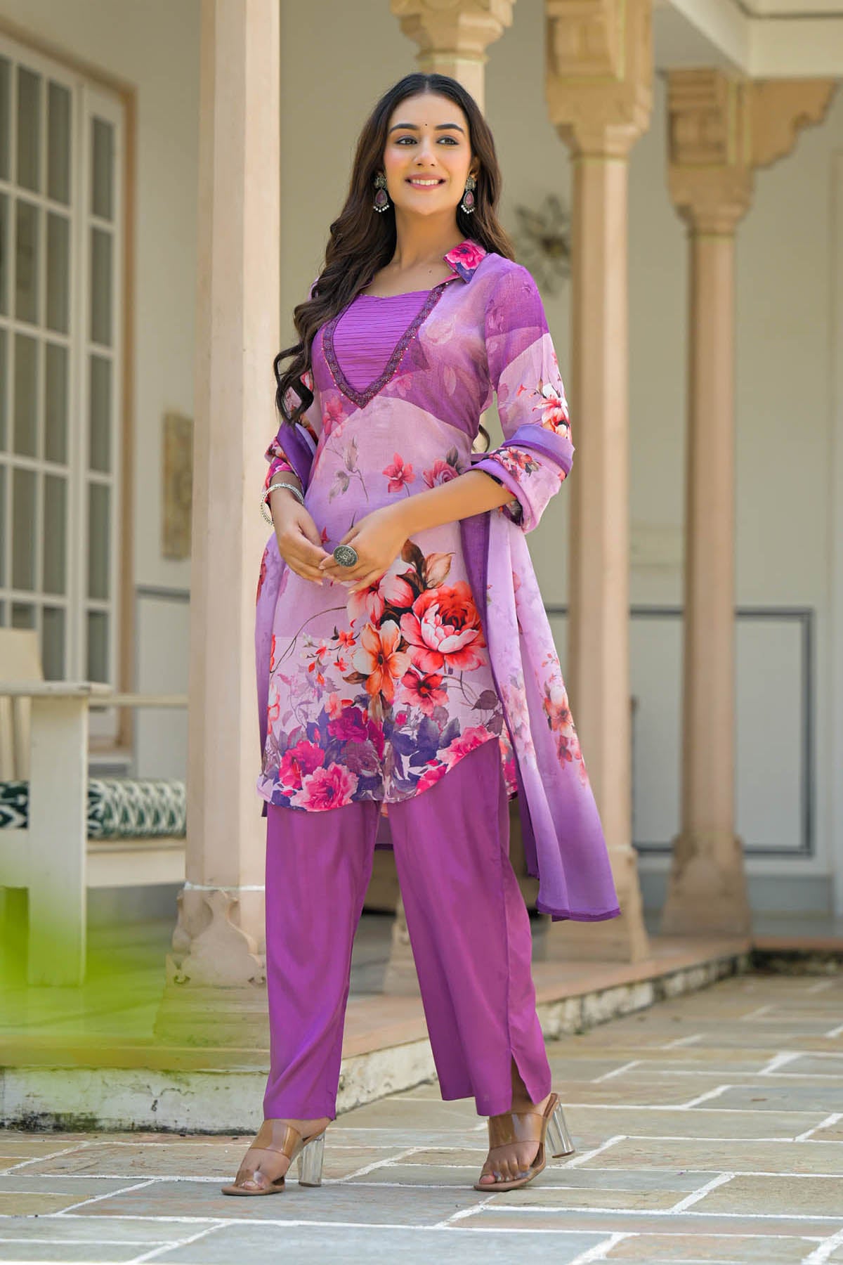 Woman in a purple floral outfit standing in front of classical architecture