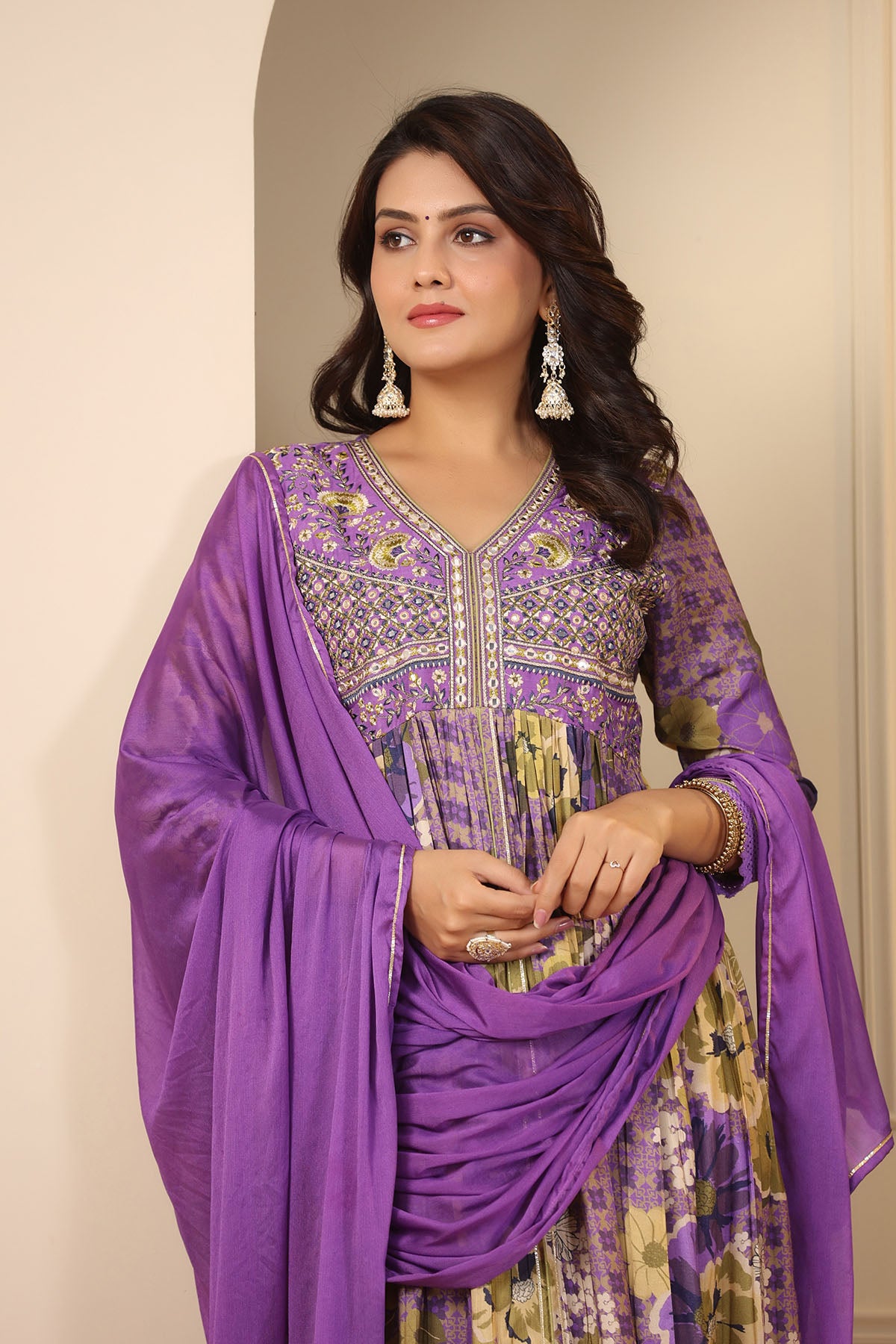 Woman wearing a purple and green traditional outfit with a plain background