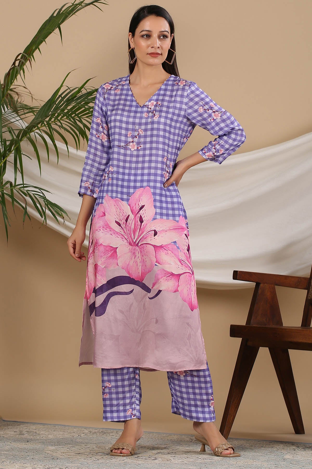 Woman wearing a purple and pink checkered outfit with floral design against a beige background