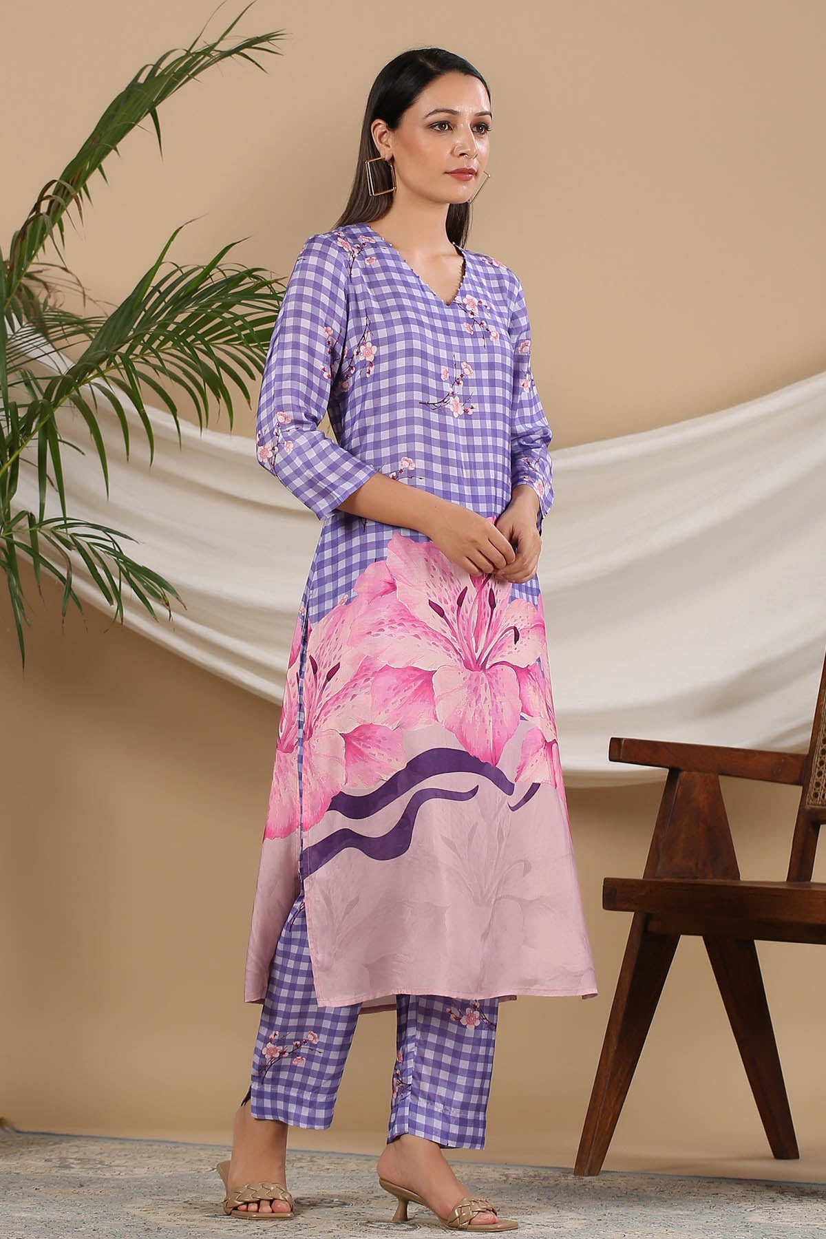 Woman wearing a checkered kurta with a pink floral skirt against a beige background