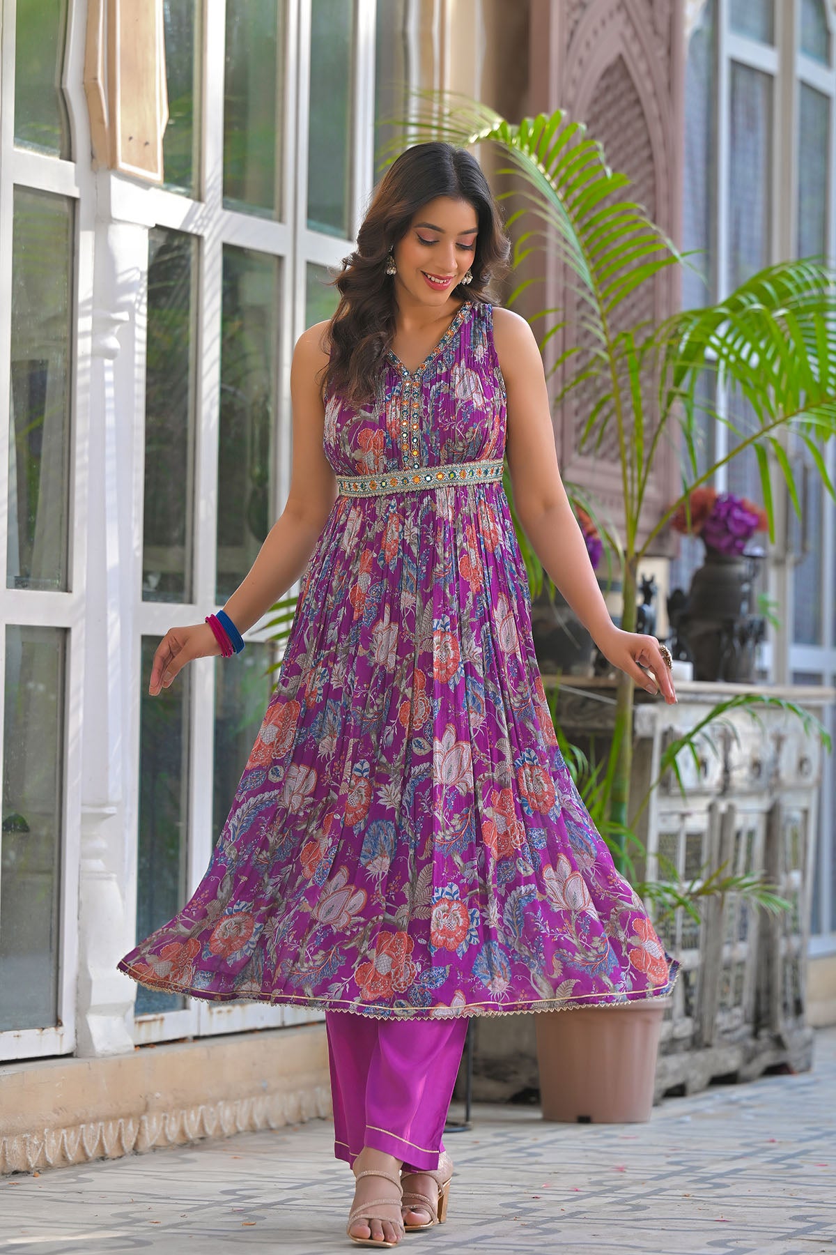 Woman wearing a colorful floral dress and purple pants outdoors.