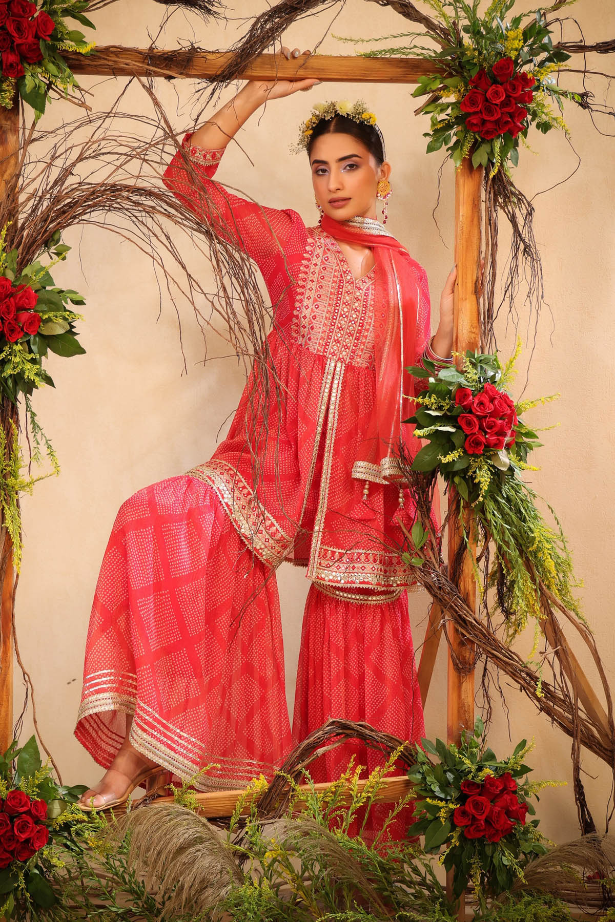 Woman in a red traditional outfit with floral decorations and branches.