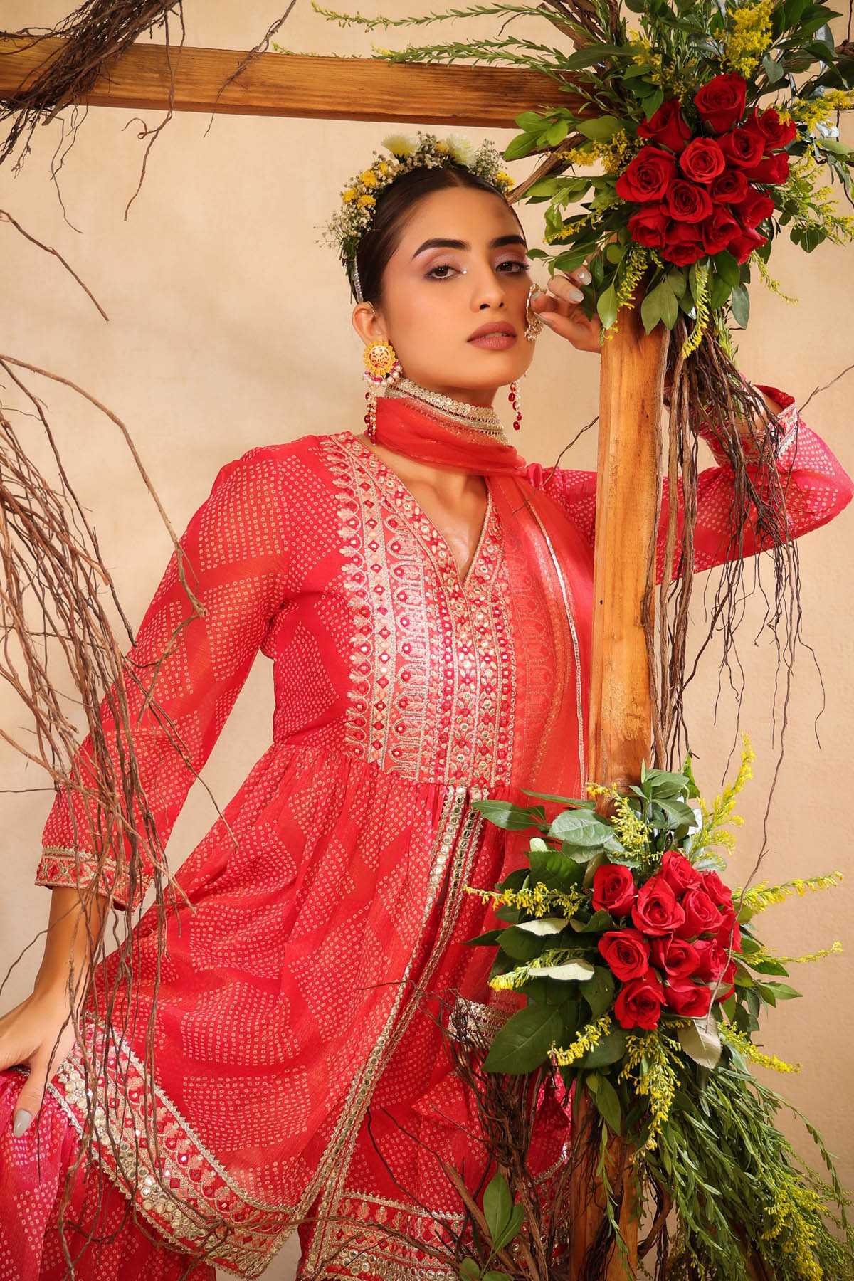 Woman in a red traditional outfit holding flowers against a beige background