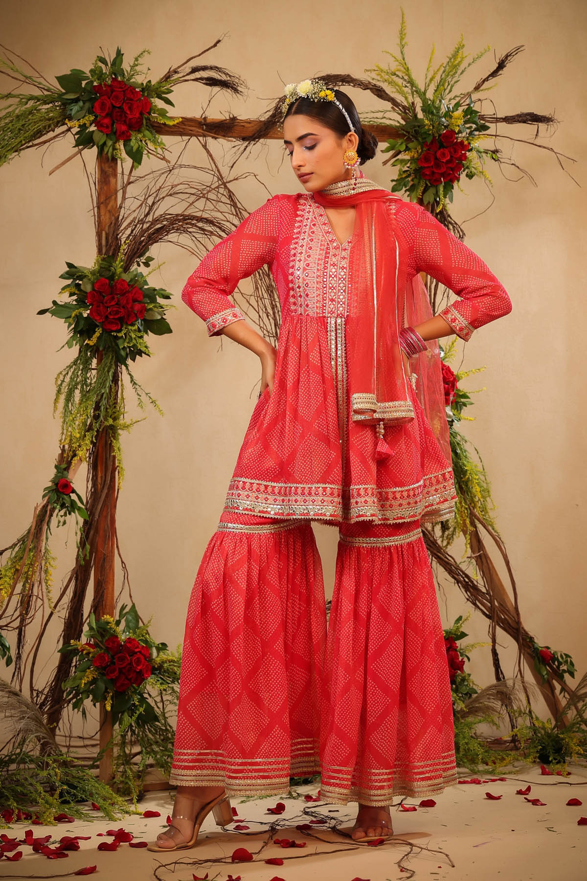 Woman in a traditional pink outfit with floral decorations and red flowers on a beige background