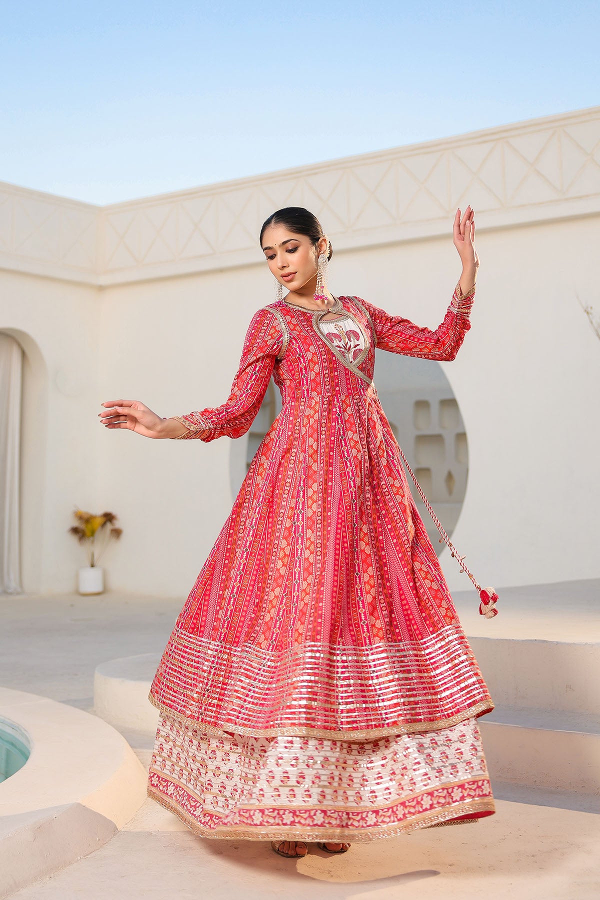 Woman in a red and white traditional outfit standing in a sunlit outdoor setting.