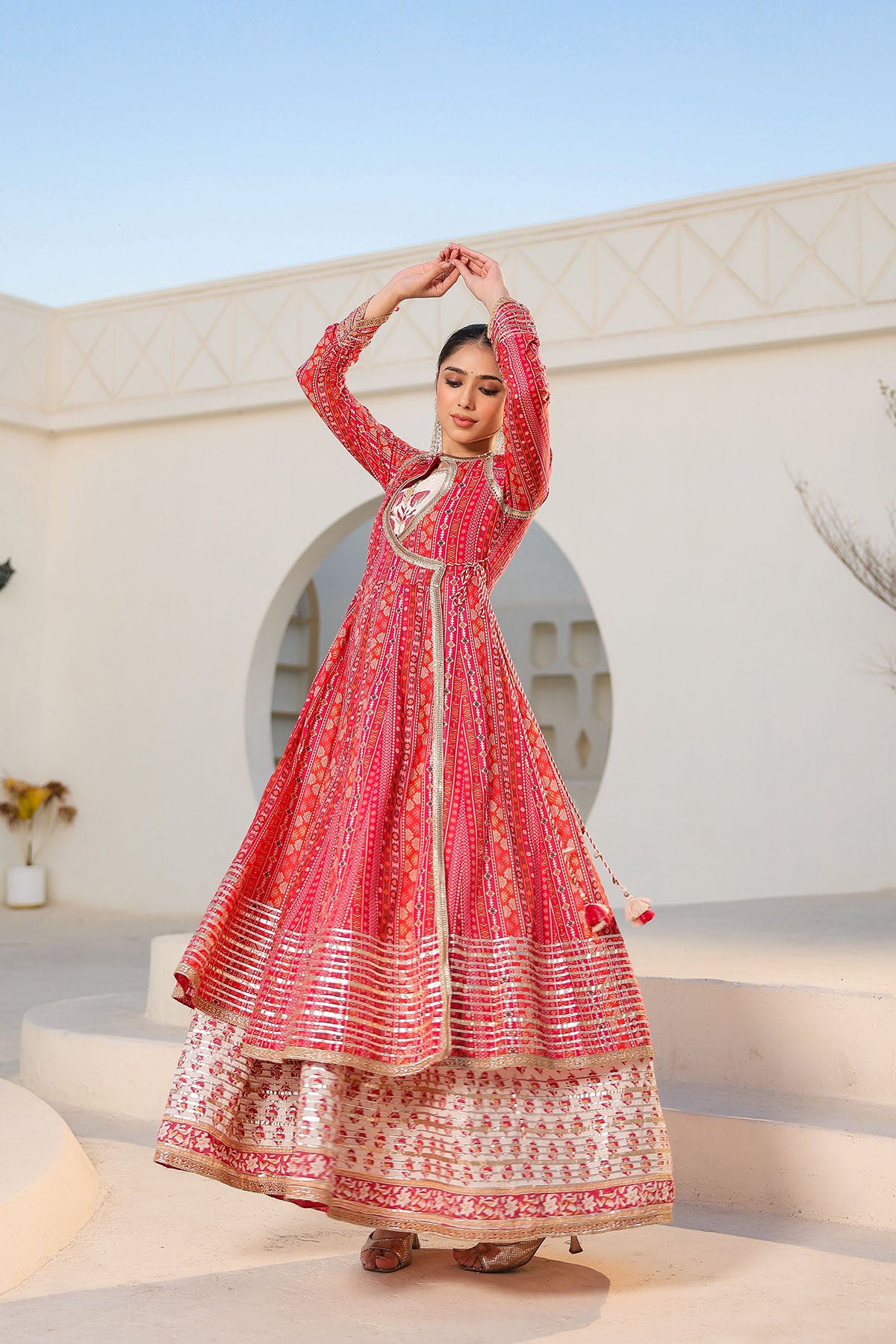Woman in a red and white traditional outfit standing against a white architectural background