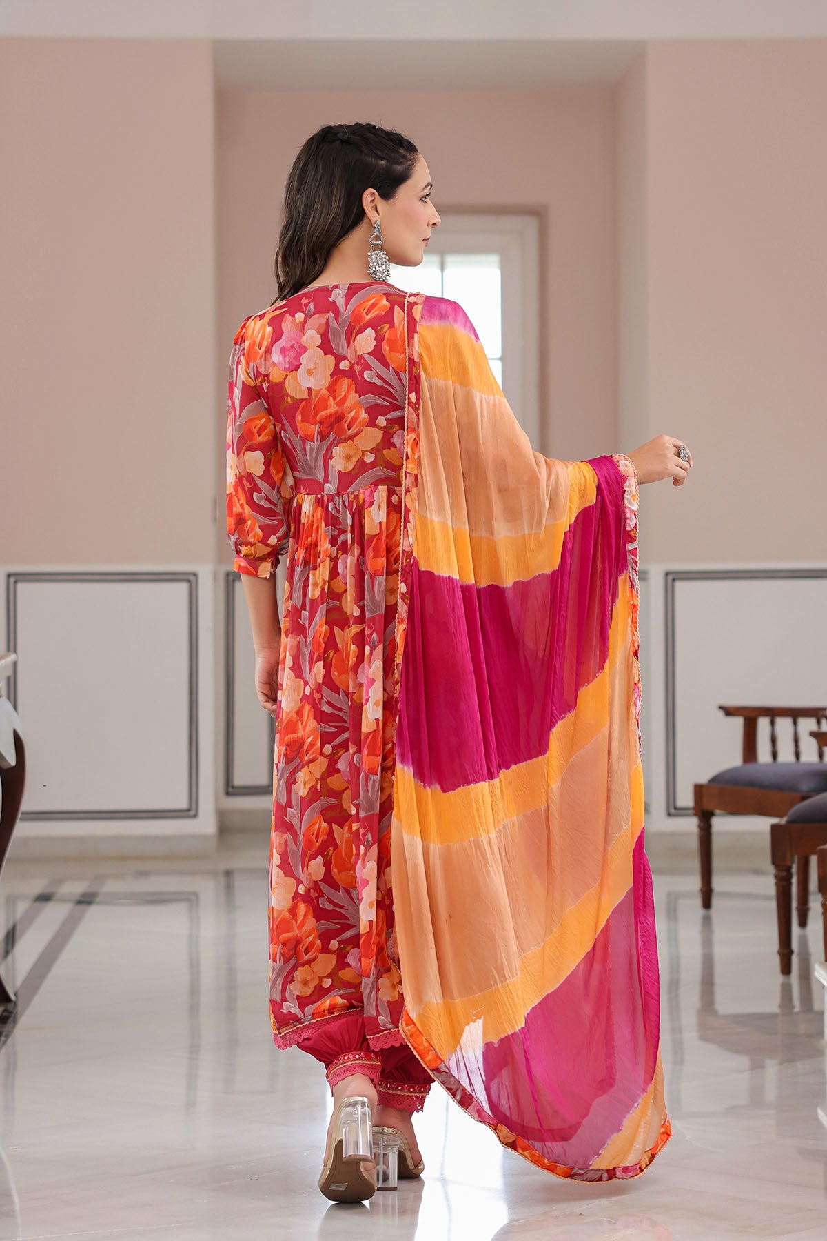 Woman wearing a colorful outfit with a floral pattern in a room.