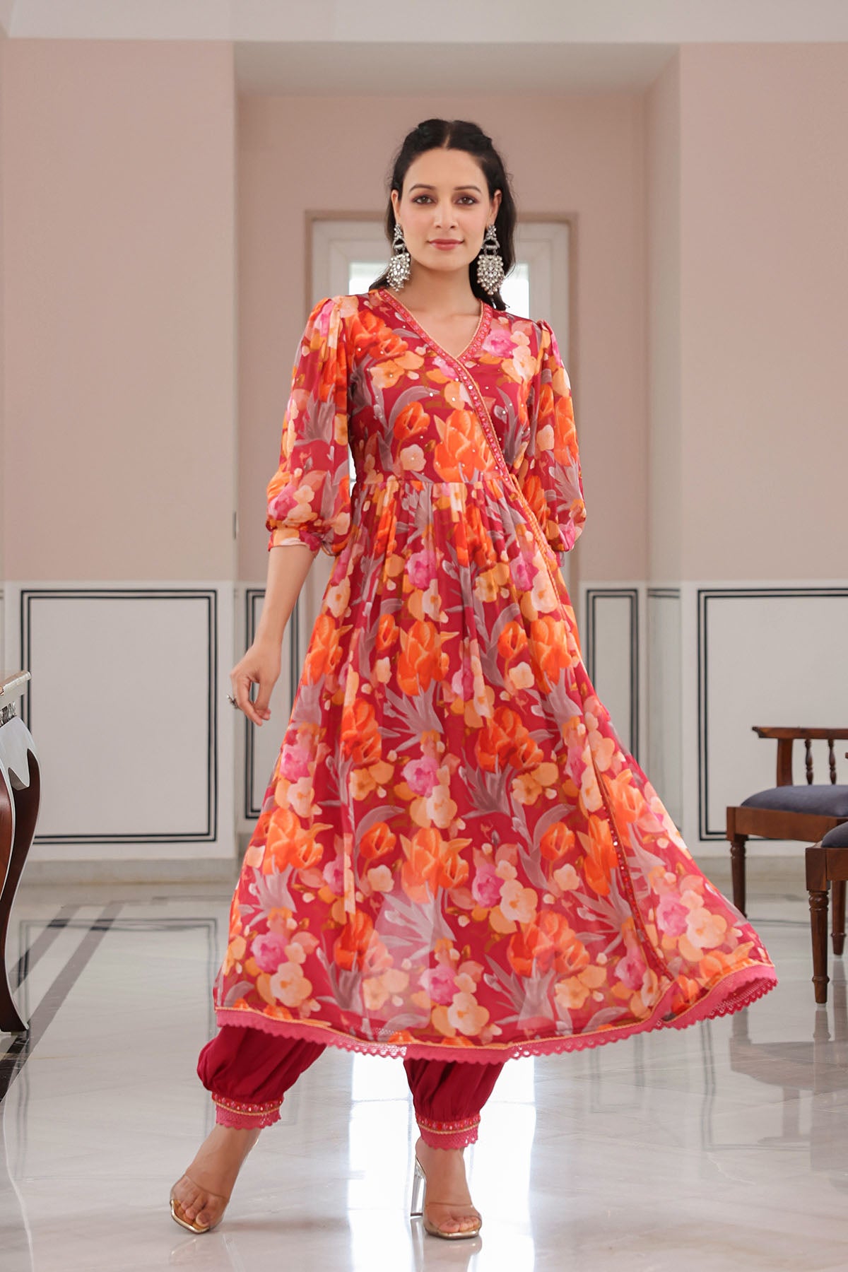 Woman wearing a vibrant orange and pink floral dress in an indoor setting