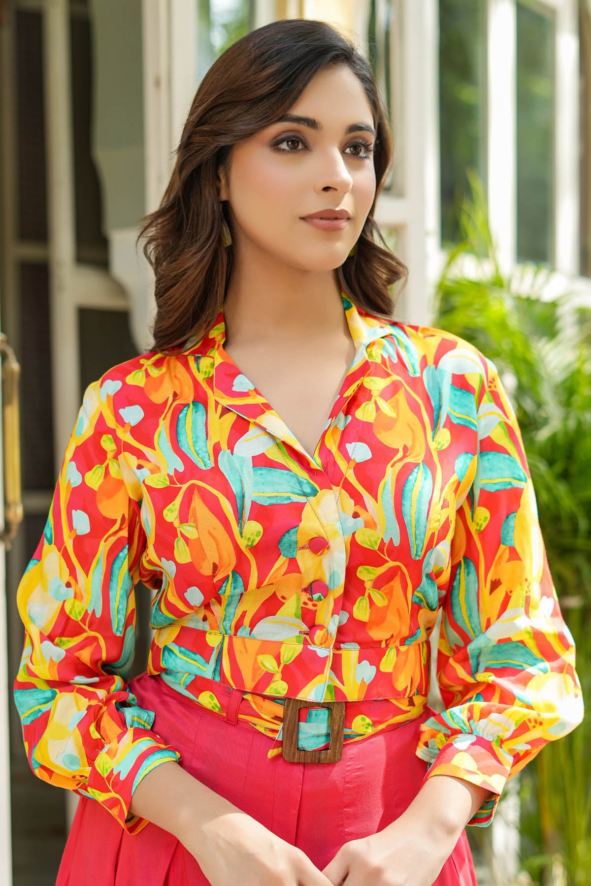 Woman wearing a colorful patterned shirt with a blurred outdoor background