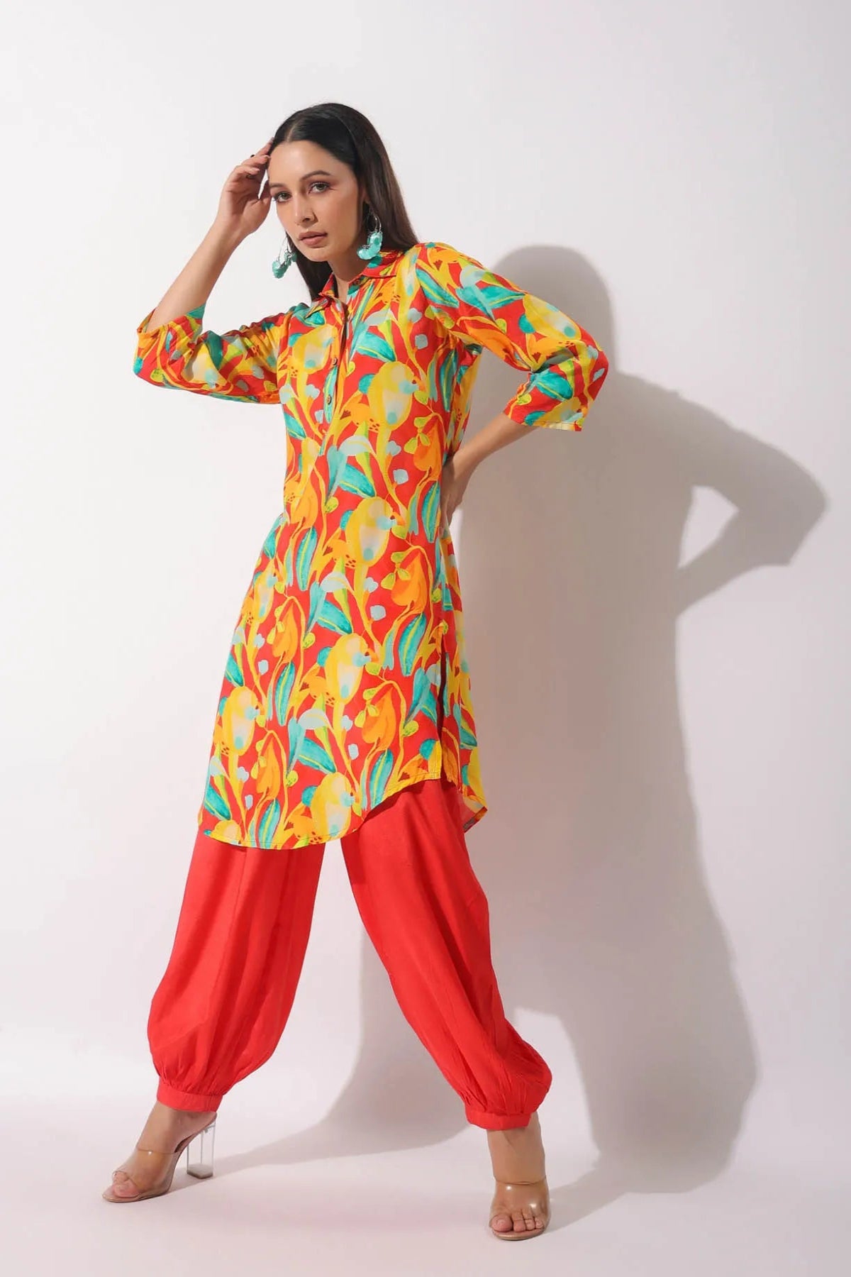 Woman wearing a colorful kurta with red pants on a white background