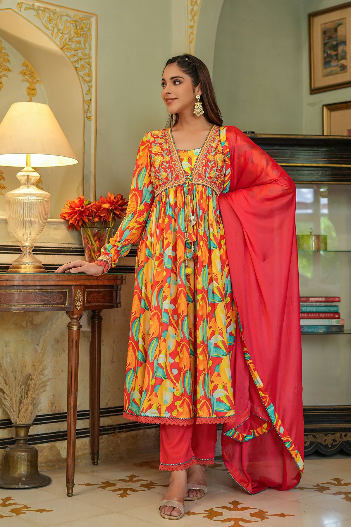 Woman in a colorful traditional outfit standing in an elegant room.