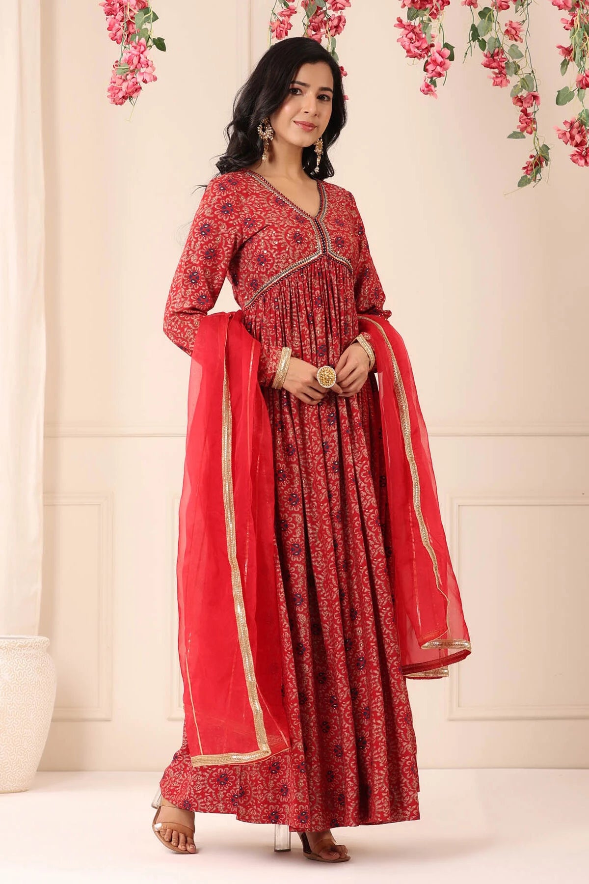 Woman wearing a red traditional outfit with a floral background