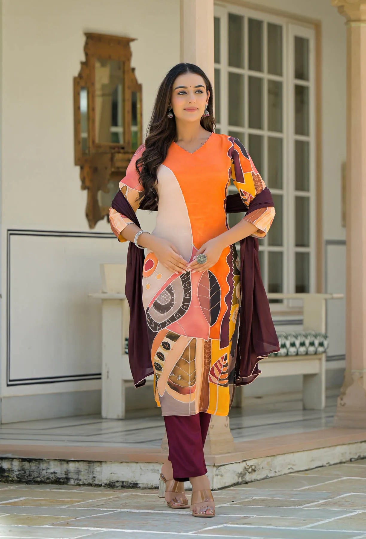 Woman wearing a colorful outfit with abstract patterns in an outdoor setting.