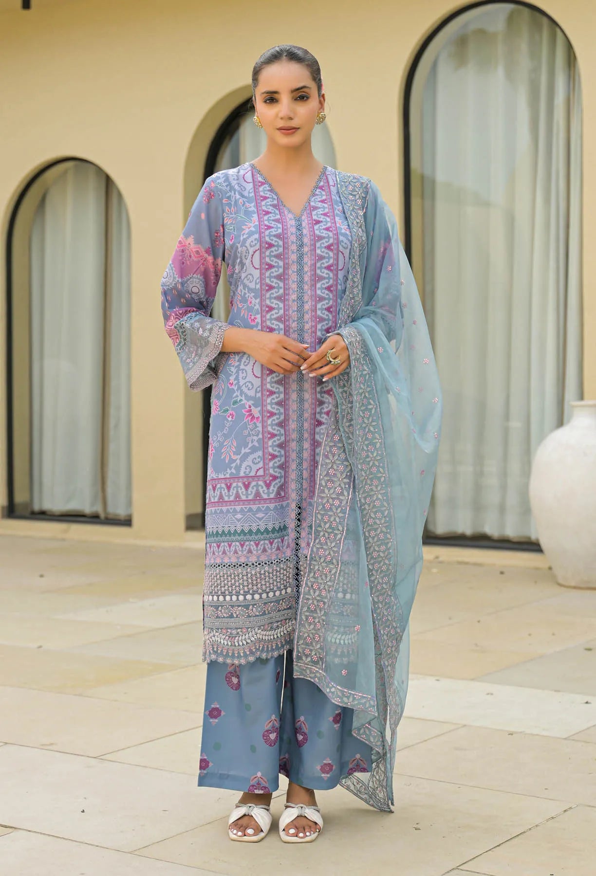 Woman wearing a traditional outfit with a floral design in an outdoor setting.