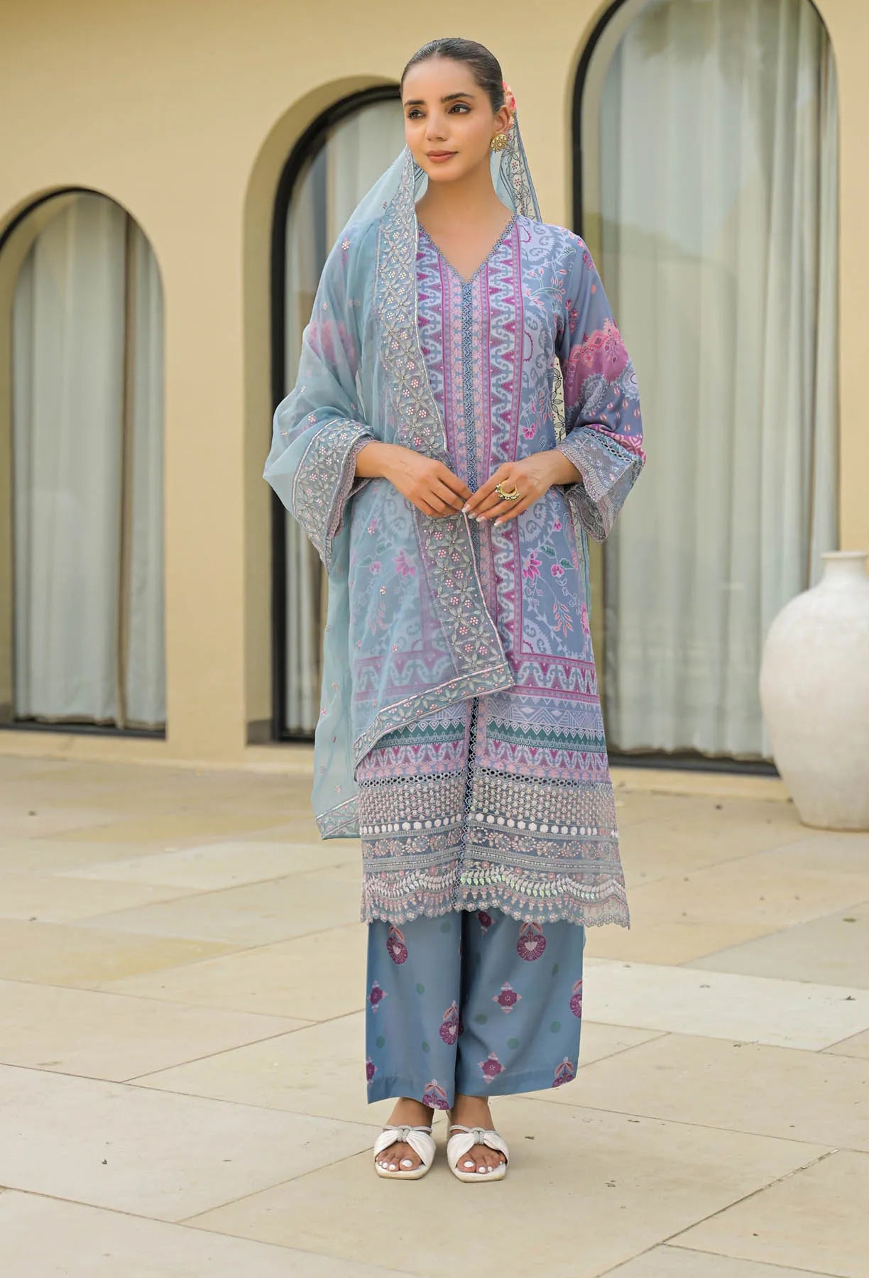 Woman wearing a light blue traditional outfit with a matching dupatta in an outdoor setting.