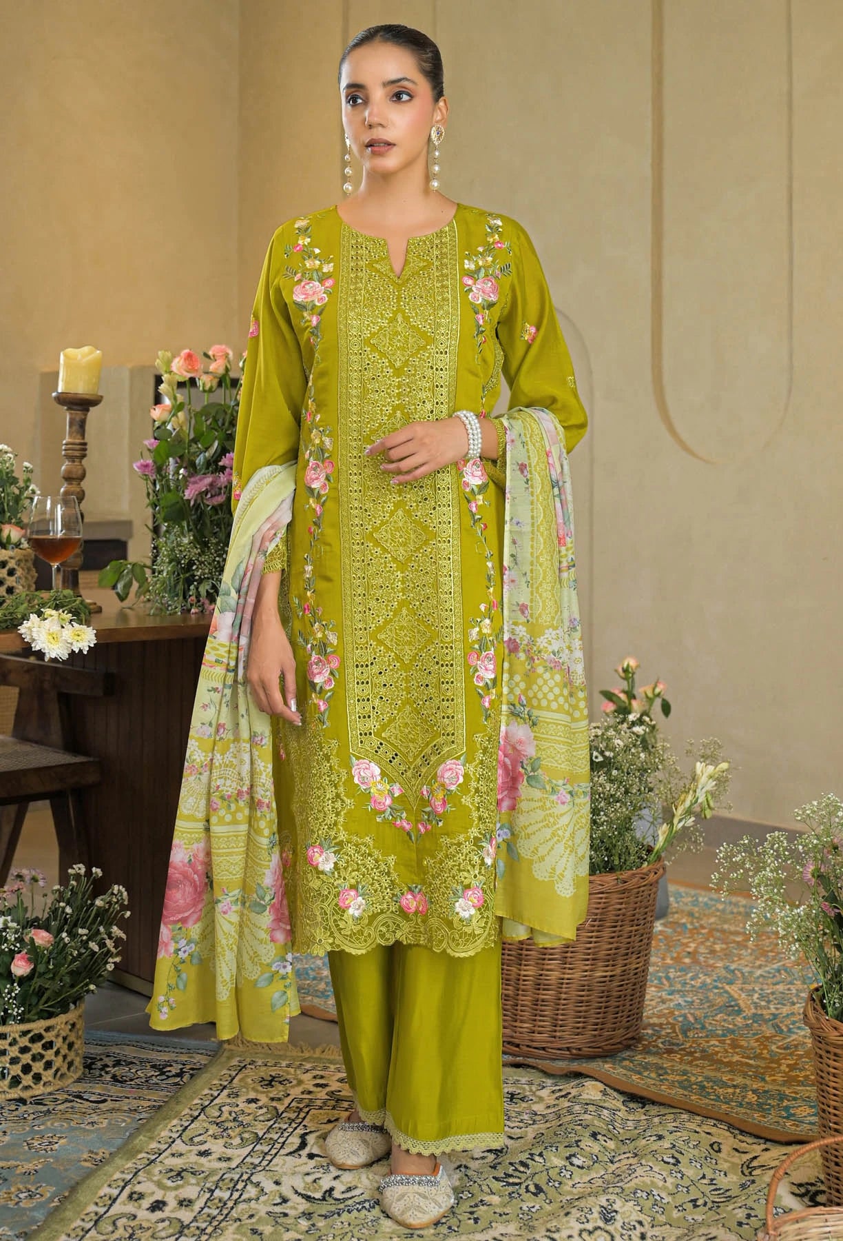 Woman wearing a green embroidered outfit with floral patterns in an indoor setting.