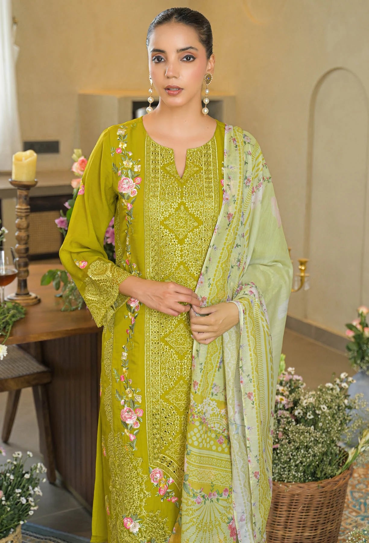 Woman in a green embroidered outfit standing indoors with decorative elements.