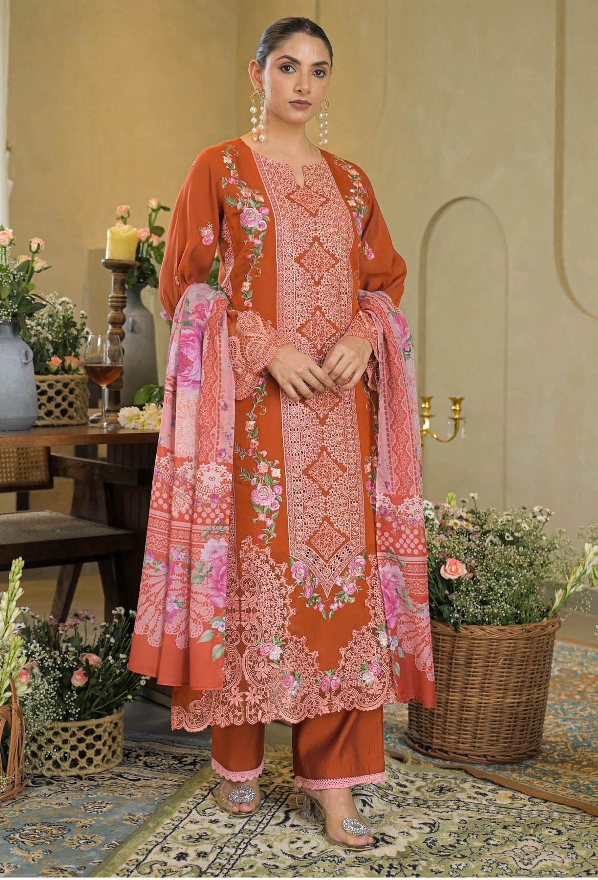 Woman in a traditional outfit with floral patterns in a decorated room.