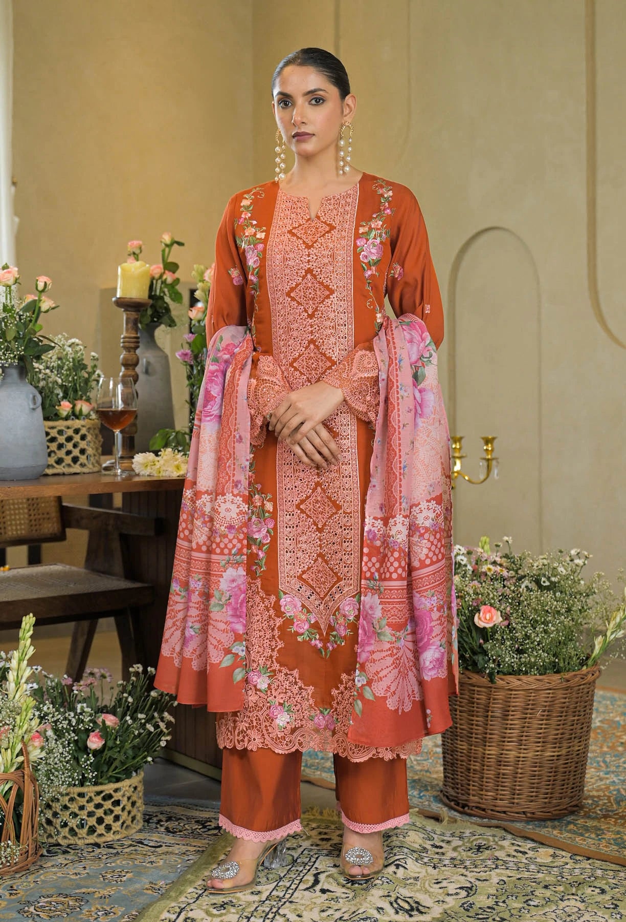 Woman wearing a traditional outfit with floral patterns in a decorated room.