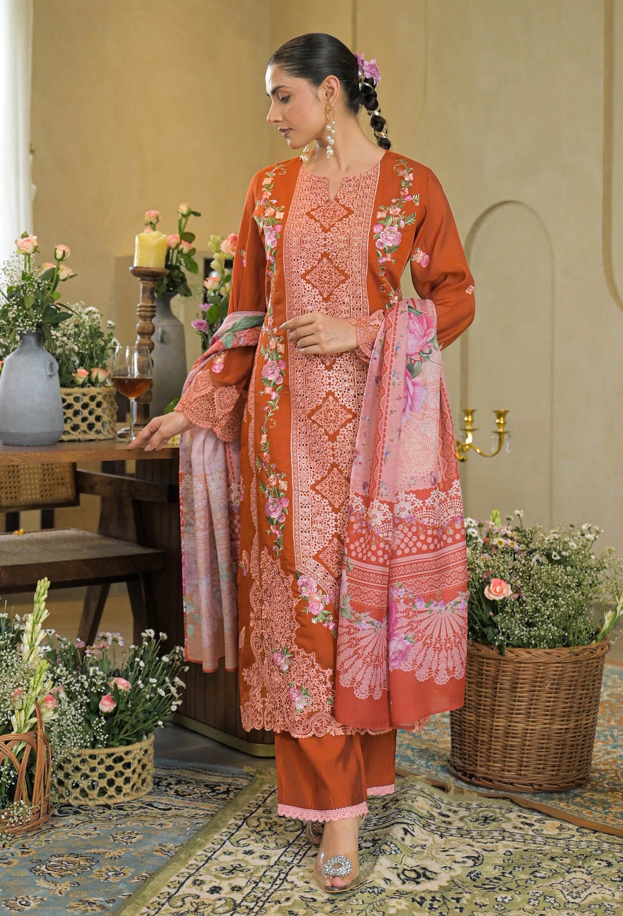 Woman in a traditional outfit with floral patterns in a decorated room.