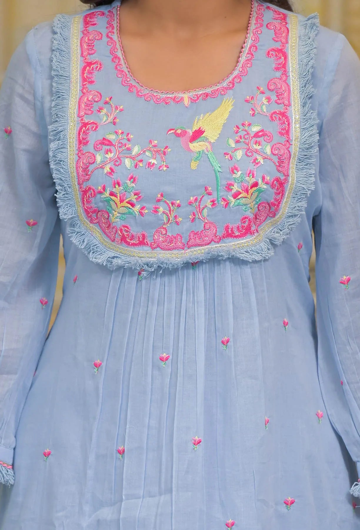 Light blue dress with pink and yellow embroidery on a plain background