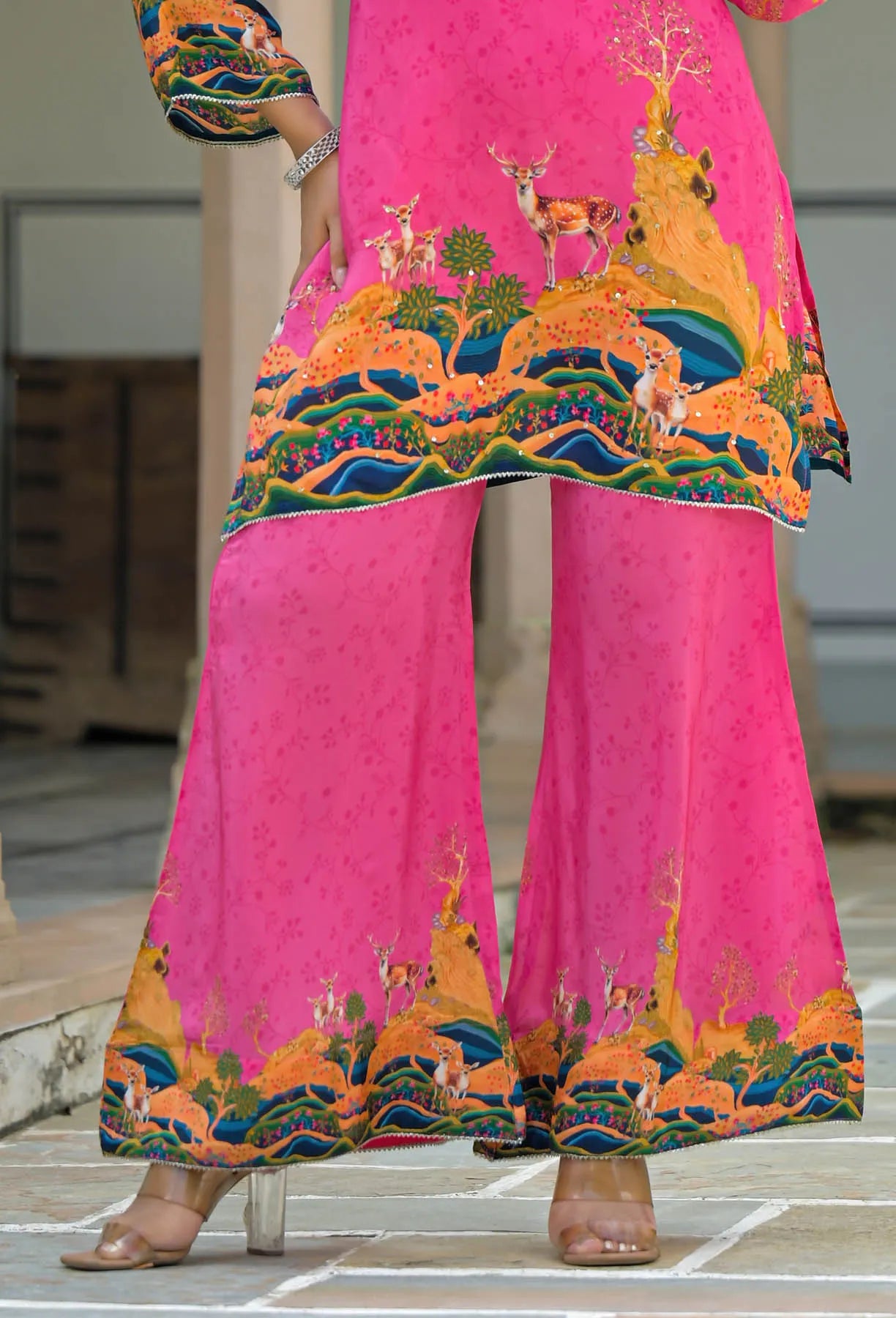 Bright pink traditional outfit with colorful deer design on a patterned floor.