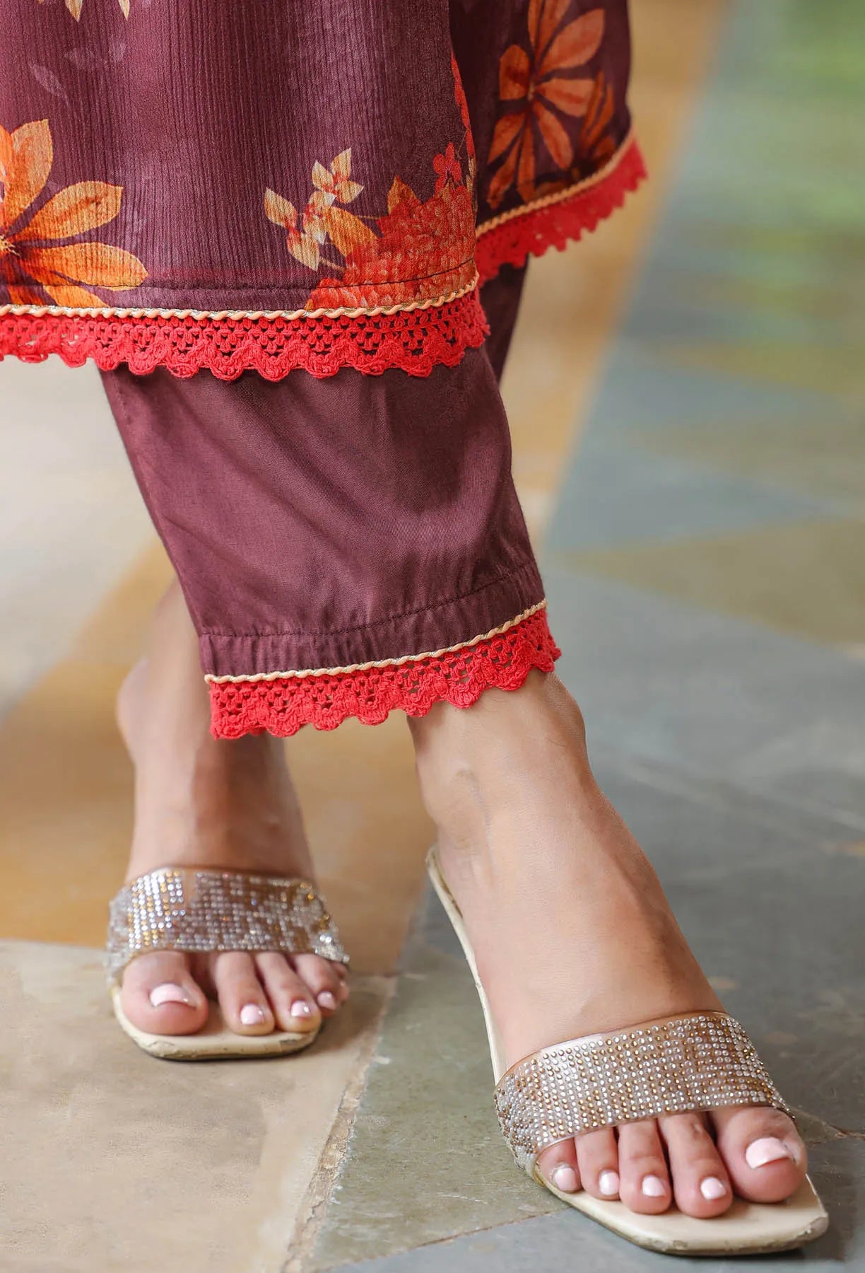 Close-up of feet wearing silver sandals with a person in traditional attire.