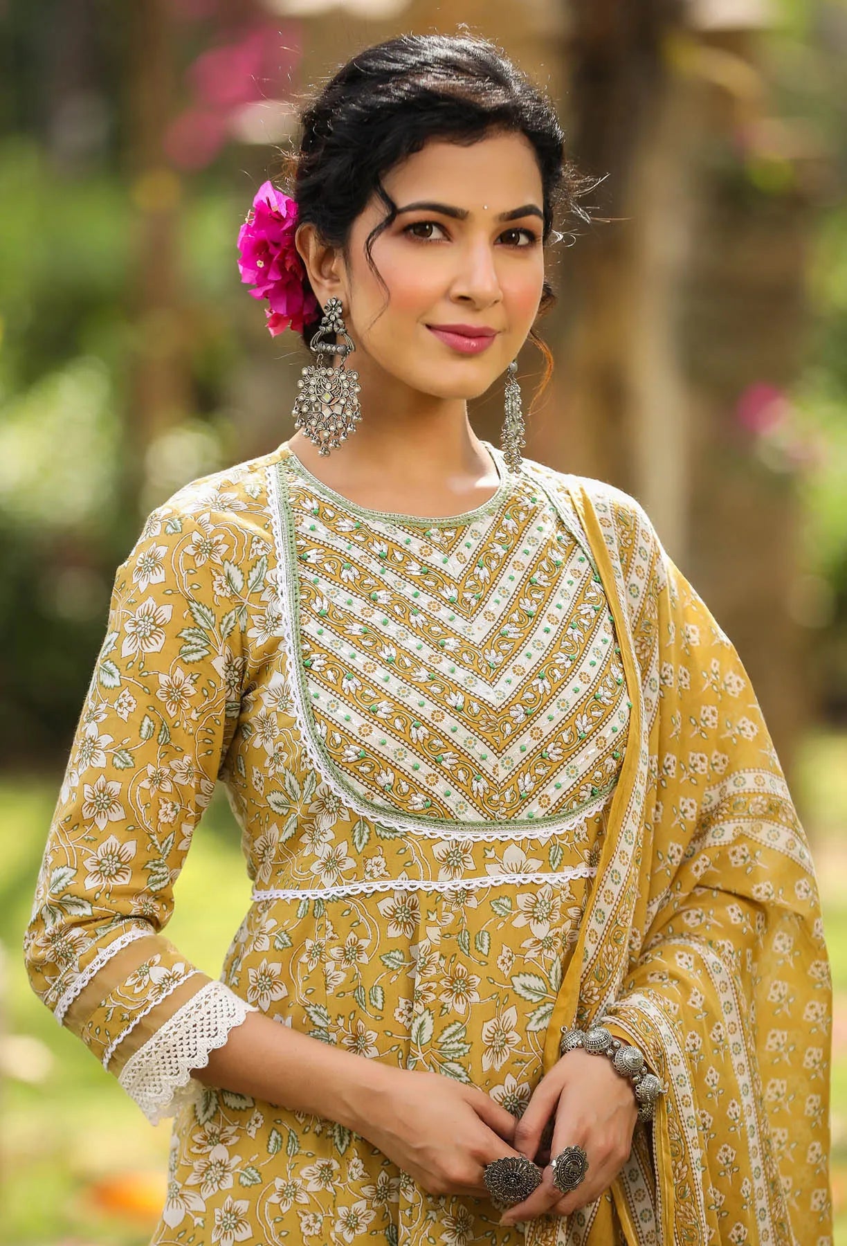 Woman wearing a yellow traditional outfit with floral patterns in a natural setting