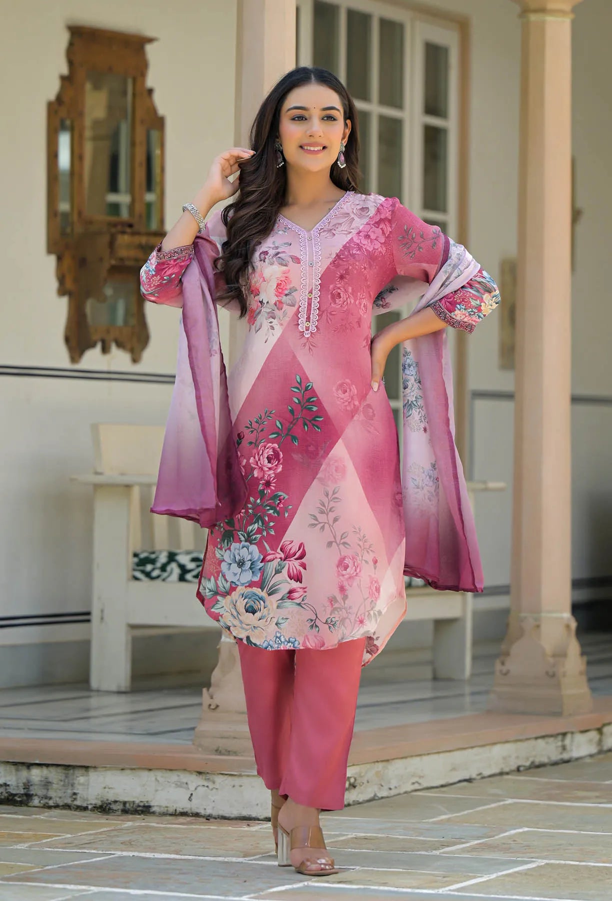 Woman in a pink floral outfit standing in an outdoor setting.