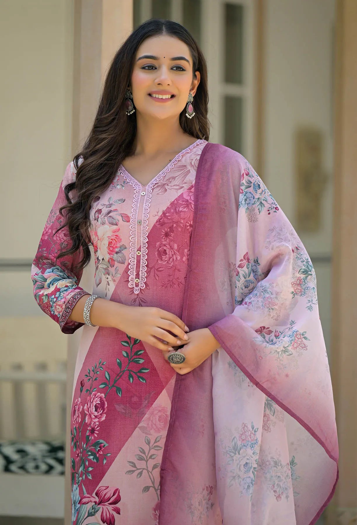 Woman wearing a pink floral outfit with a matching dupatta outdoors.