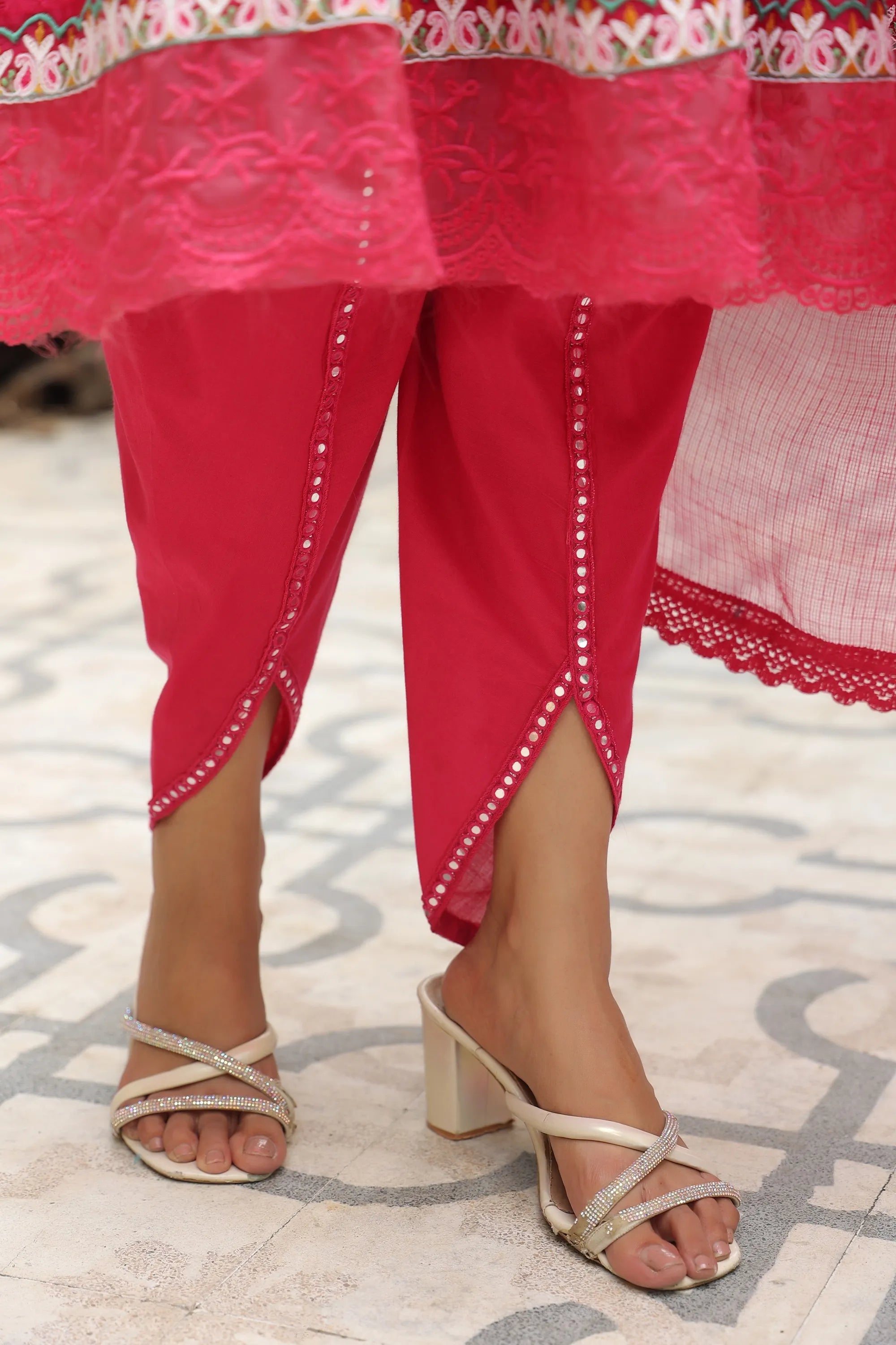 Red traditional outfit with pink dupatta and sandals on a patterned floor