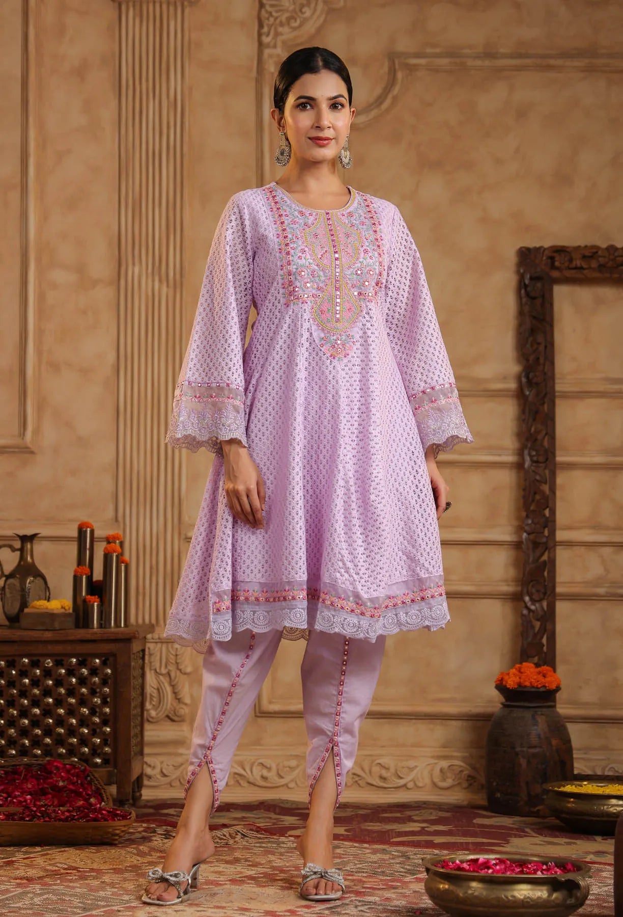 Woman wearing a light purple embroidered outfit in an ornate room.