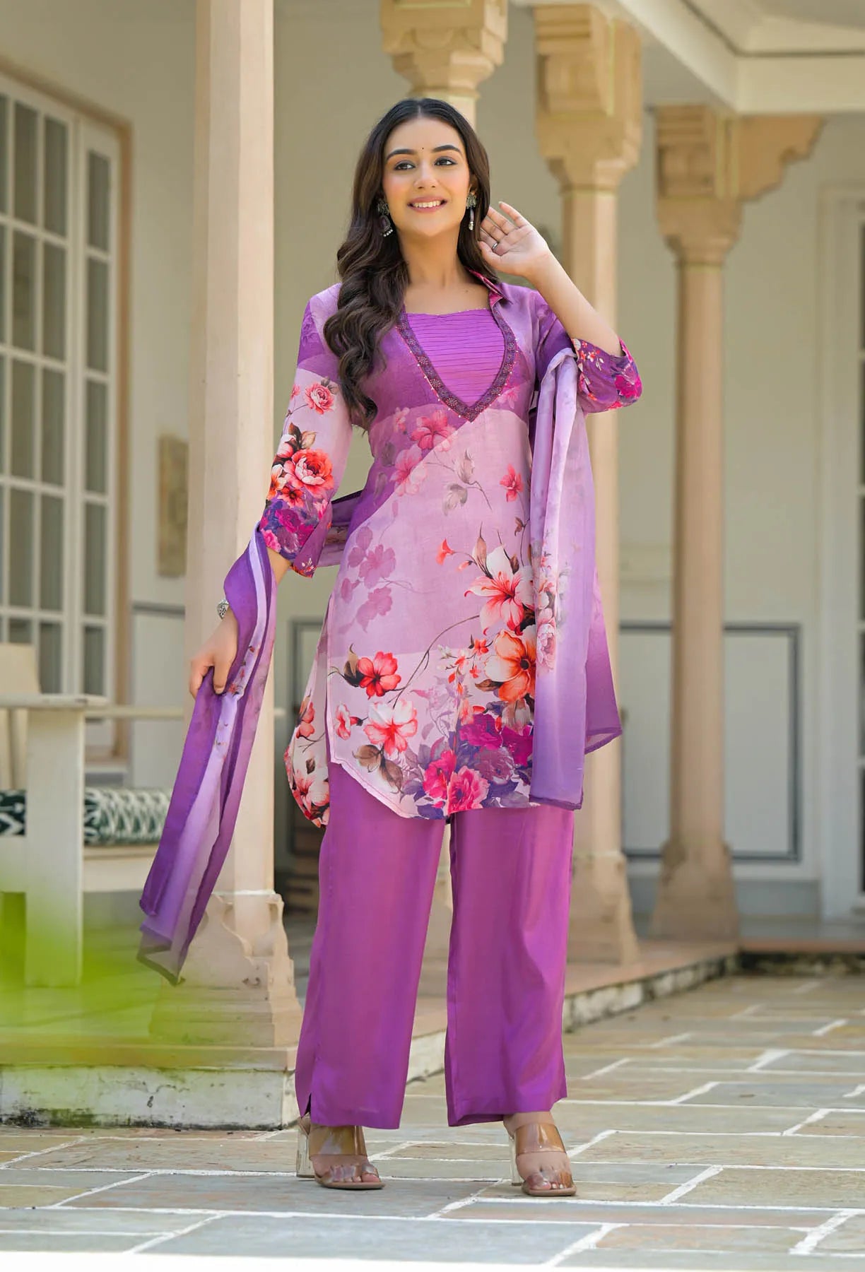 Woman in a purple floral outfit standing outdoors.