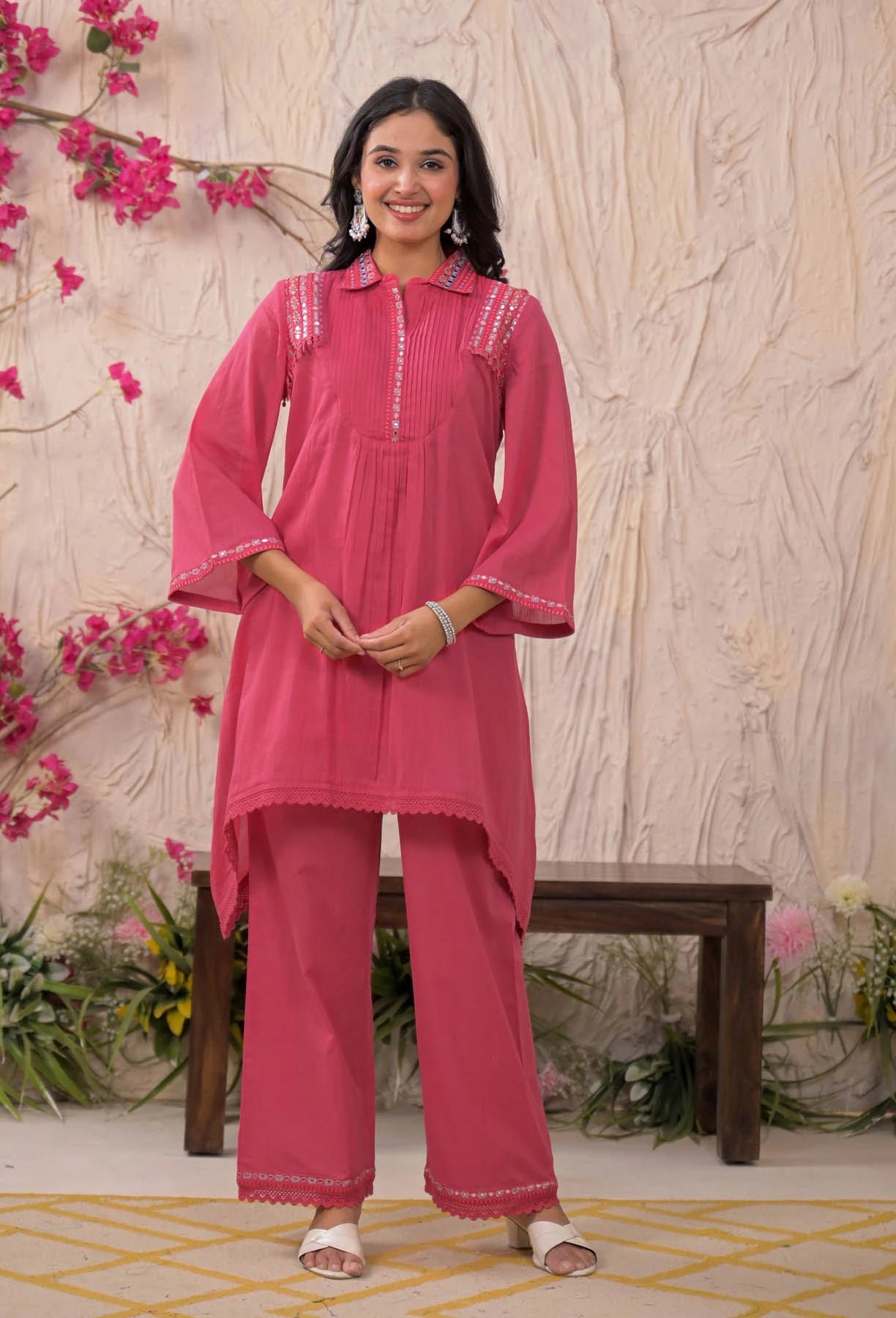 Woman in a pink traditional outfit with floral decorations in the background