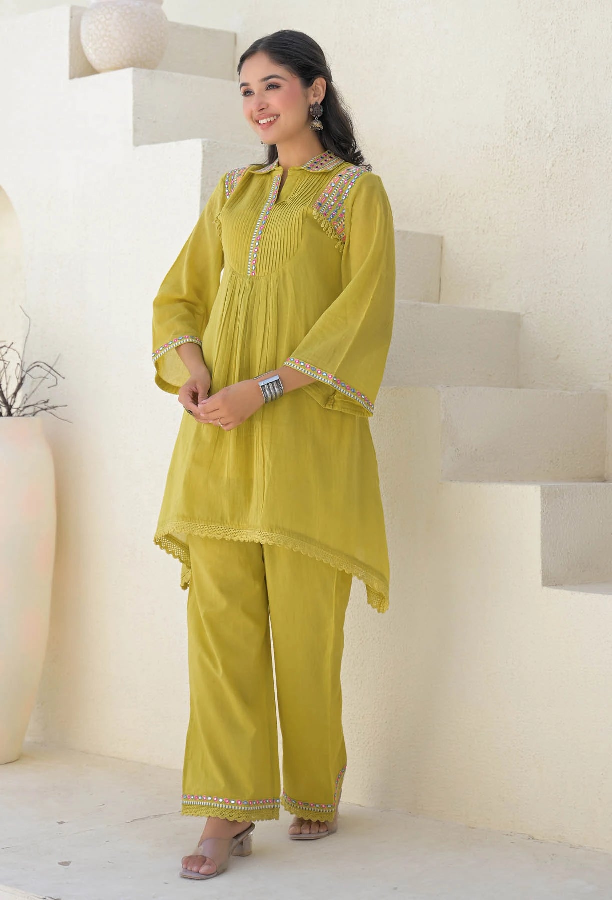 Woman wearing a yellow traditional outfit with intricate designs indoors.