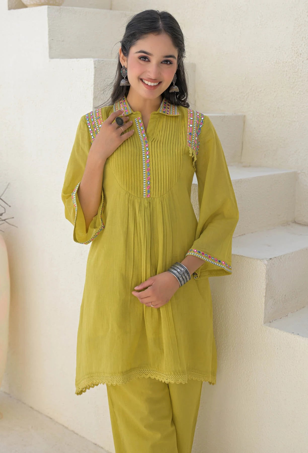 Woman wearing a yellow traditional outfit with intricate designs on a staircase background
