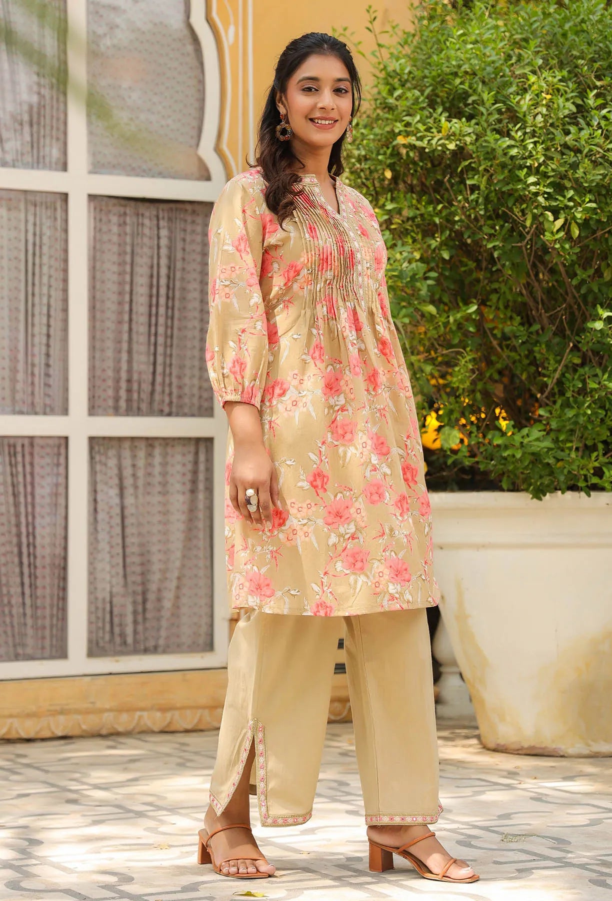 Woman wearing a floral kurta with beige pants standing outdoors.