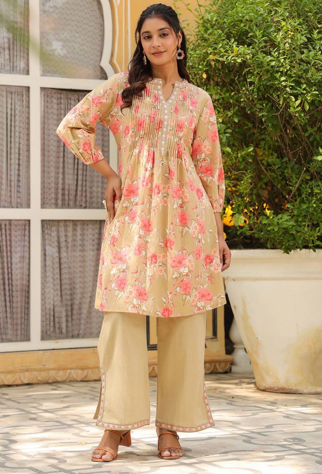 Woman wearing a floral kurta with beige pants standing outdoors.