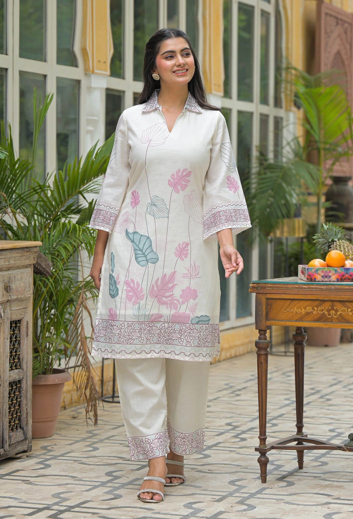 Woman wearing a white floral kurta with pants in an outdoor setting.