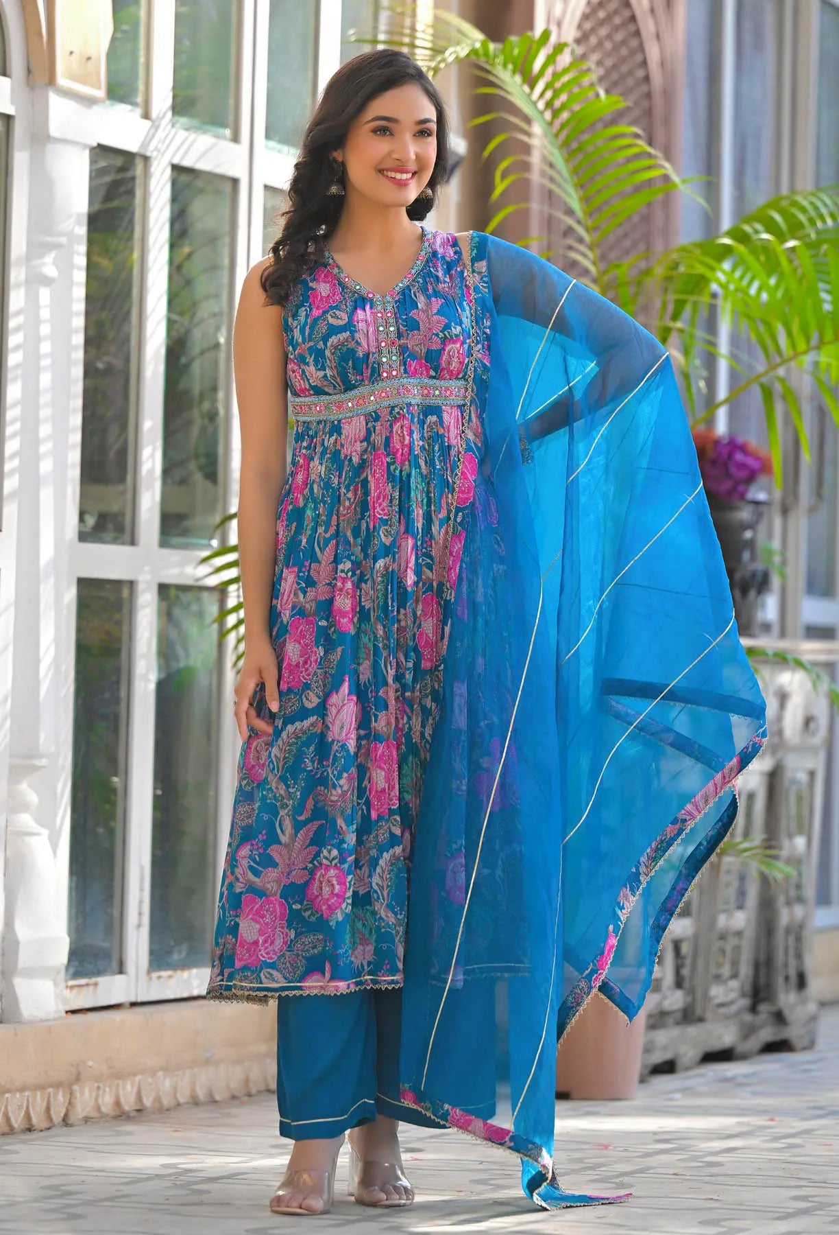 Woman wearing a blue and pink traditional outfit with a blue dupatta outdoors.