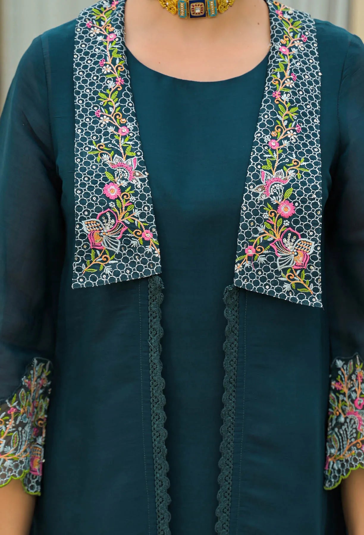Teal outfit with floral embroidery on a plain background