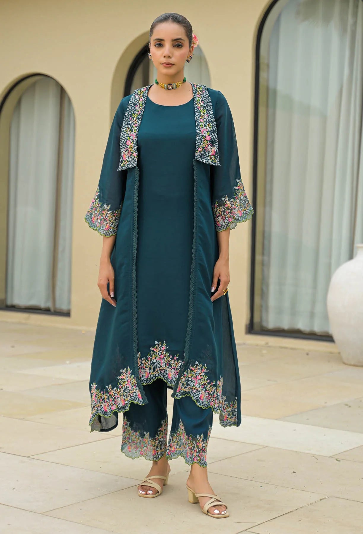 Woman wearing a teal outfit with floral embroidery in an outdoor setting