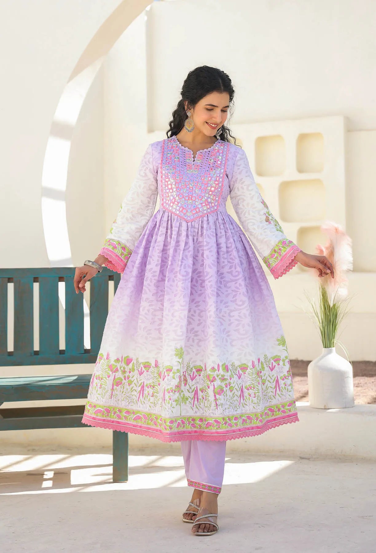 Woman wearing a light purple and pink traditional outfit with floral patterns indoors.