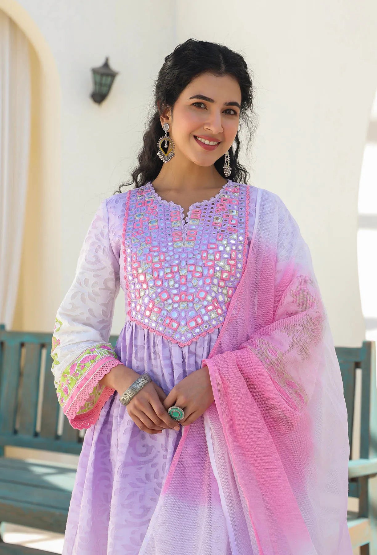 Woman wearing a colorful traditional outfit with a pink and purple dupatta.