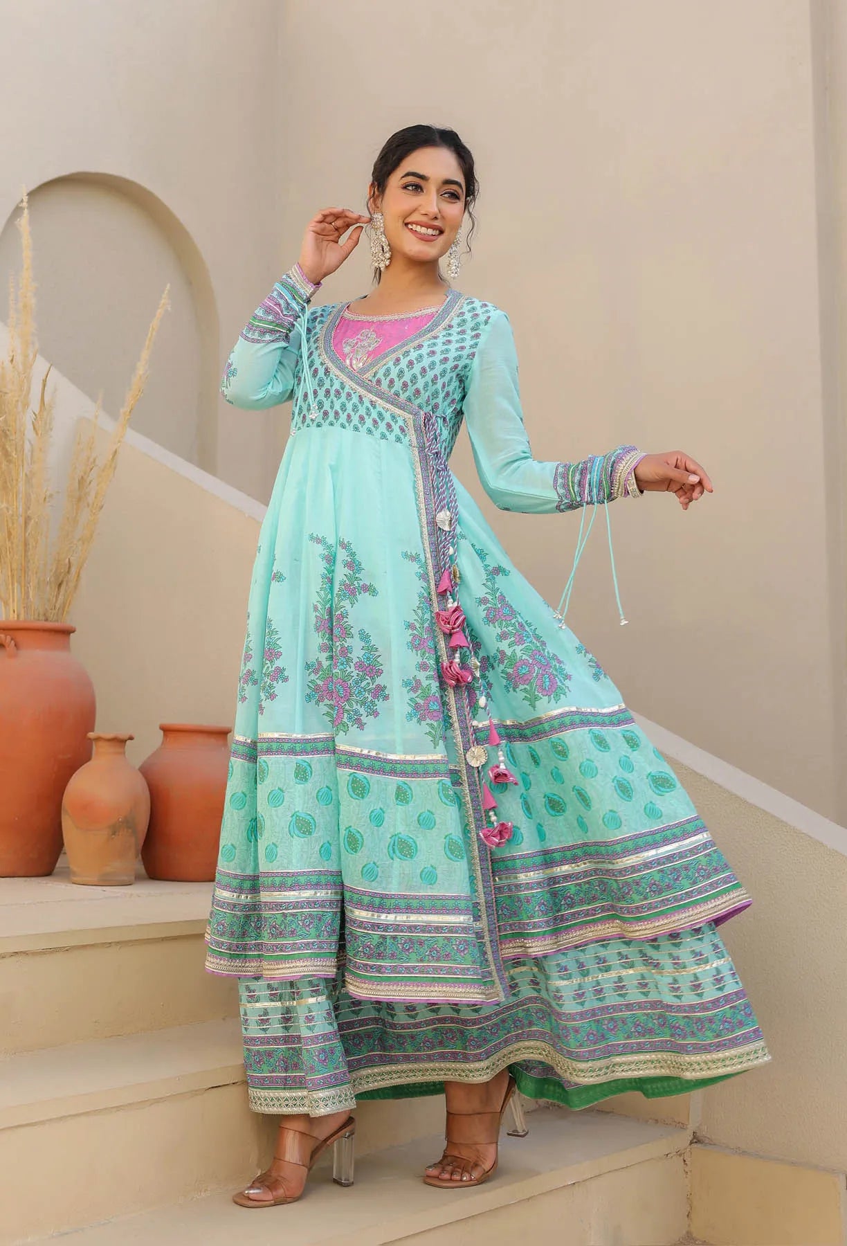 Woman wearing a light blue traditional outfit with floral patterns on a beige background
