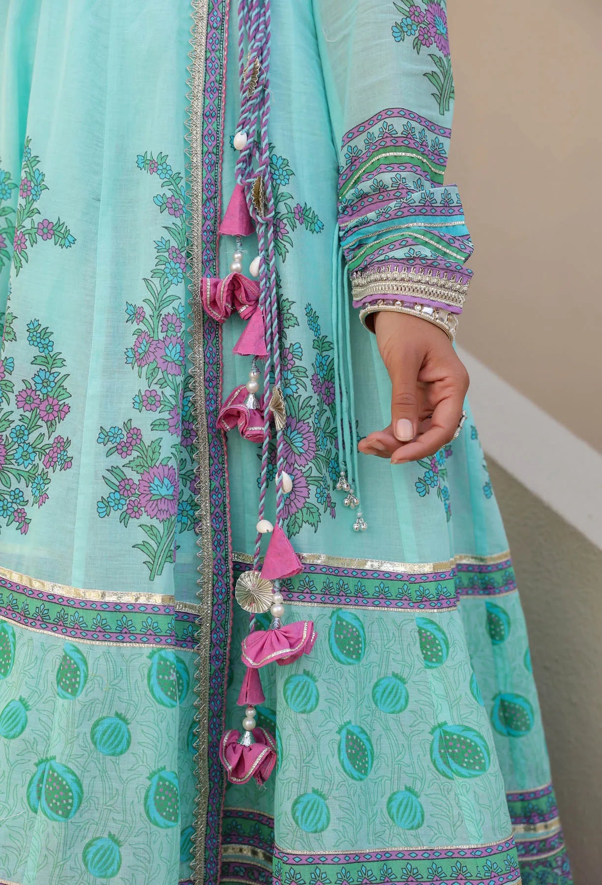 Teal embroidered traditional outfit with decorative elements on a neutral background